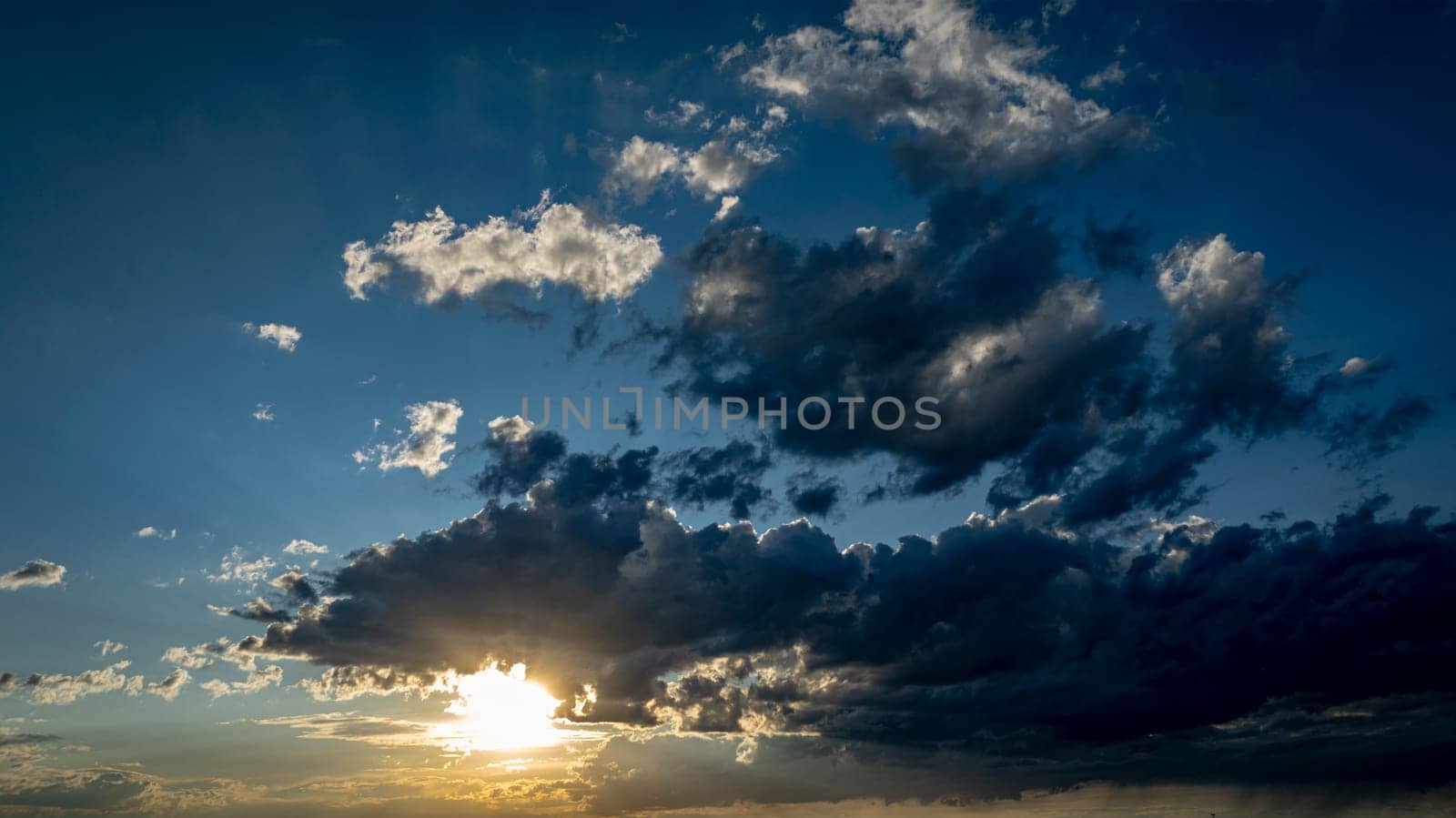 A stunning display of colors fills the sky as the sun sets, casting shadows on the clouds and creating a tranquil atmosphere during the evening hours.