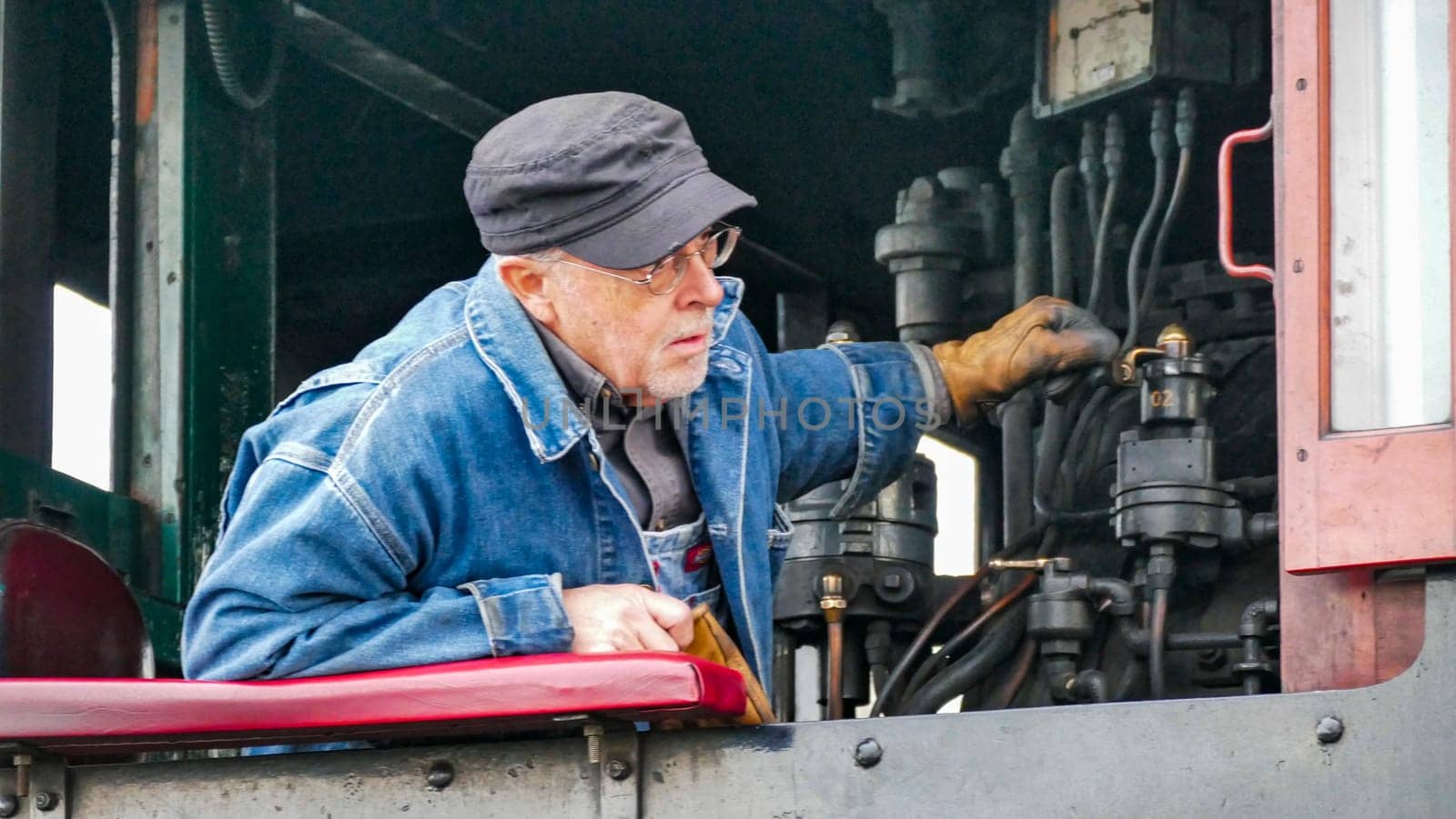 Strasburg, Pennsylvania, USA, December 31, 2024 - James Rice, A dedicated engineer adjusts the controls of a steam engine at a historic railway station, showcasing his expertise in maintaining vintage machinery on an autumn day.