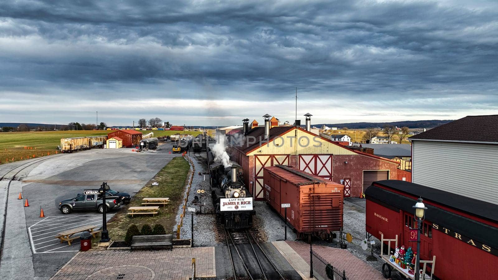 Ronks, Pennsylvania, USA, December 31, 2024 - A steam engine releases a plume of smoke as it prepares for arrival at an old railroad station. Celebrating James Rice Retirement after 51 years.