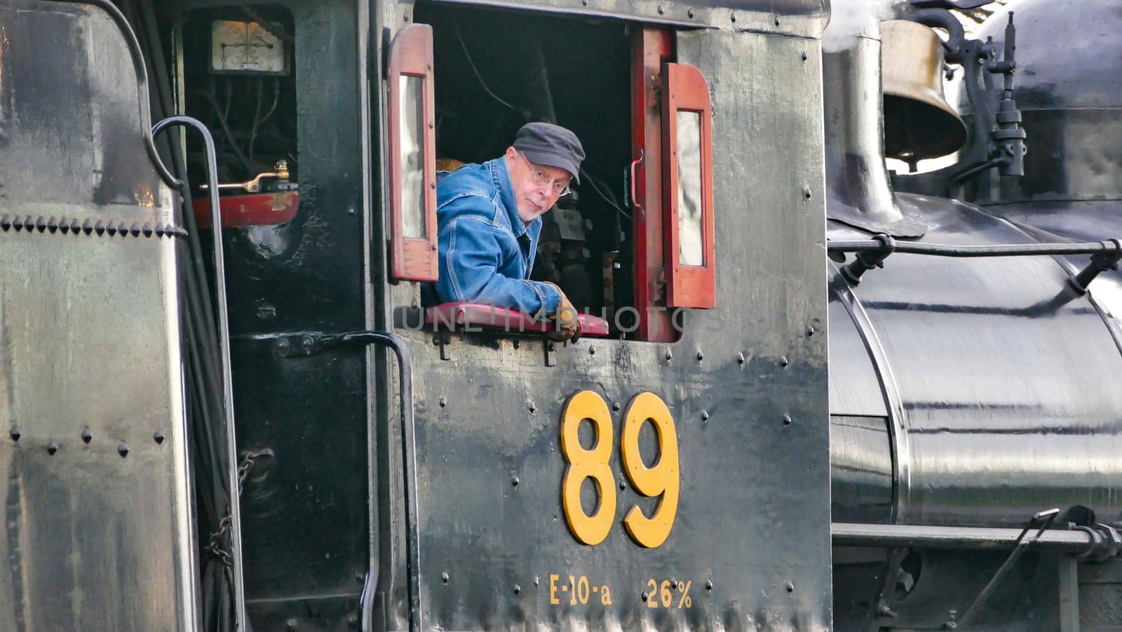 Strasburg, Pennsylvania, USA, December 31, 2024 - James Rice, A dedicated engineer adjusts the controls of a steam engine at a historic railway station, showcasing his expertise in maintaining vintage machinery on an autumn day.