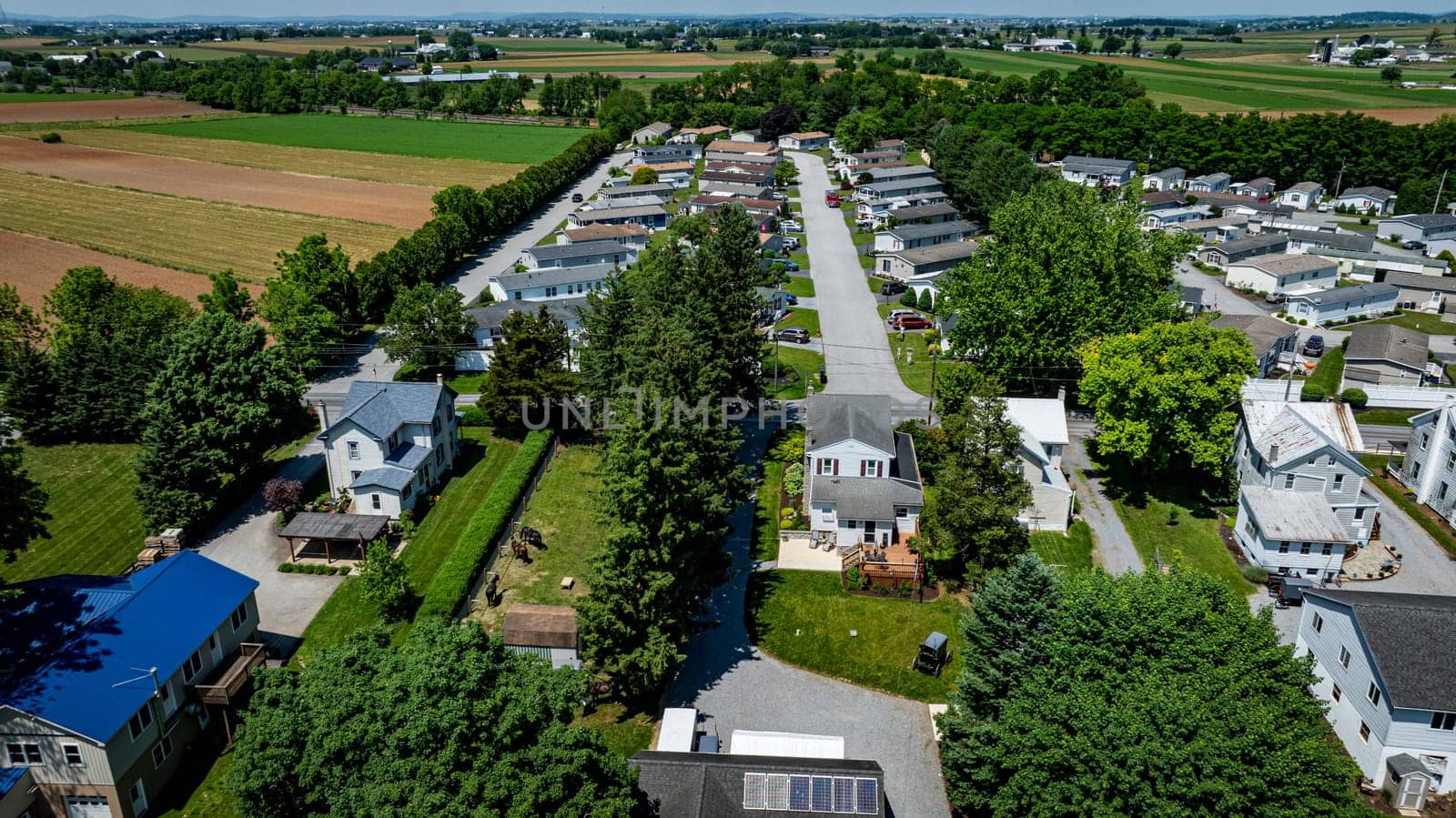 Residential Mobile, Manufactured, Prefab, Home Park with many houses and trees. The houses are white and the trees are green. The sky is cloudy and the houses are spread out