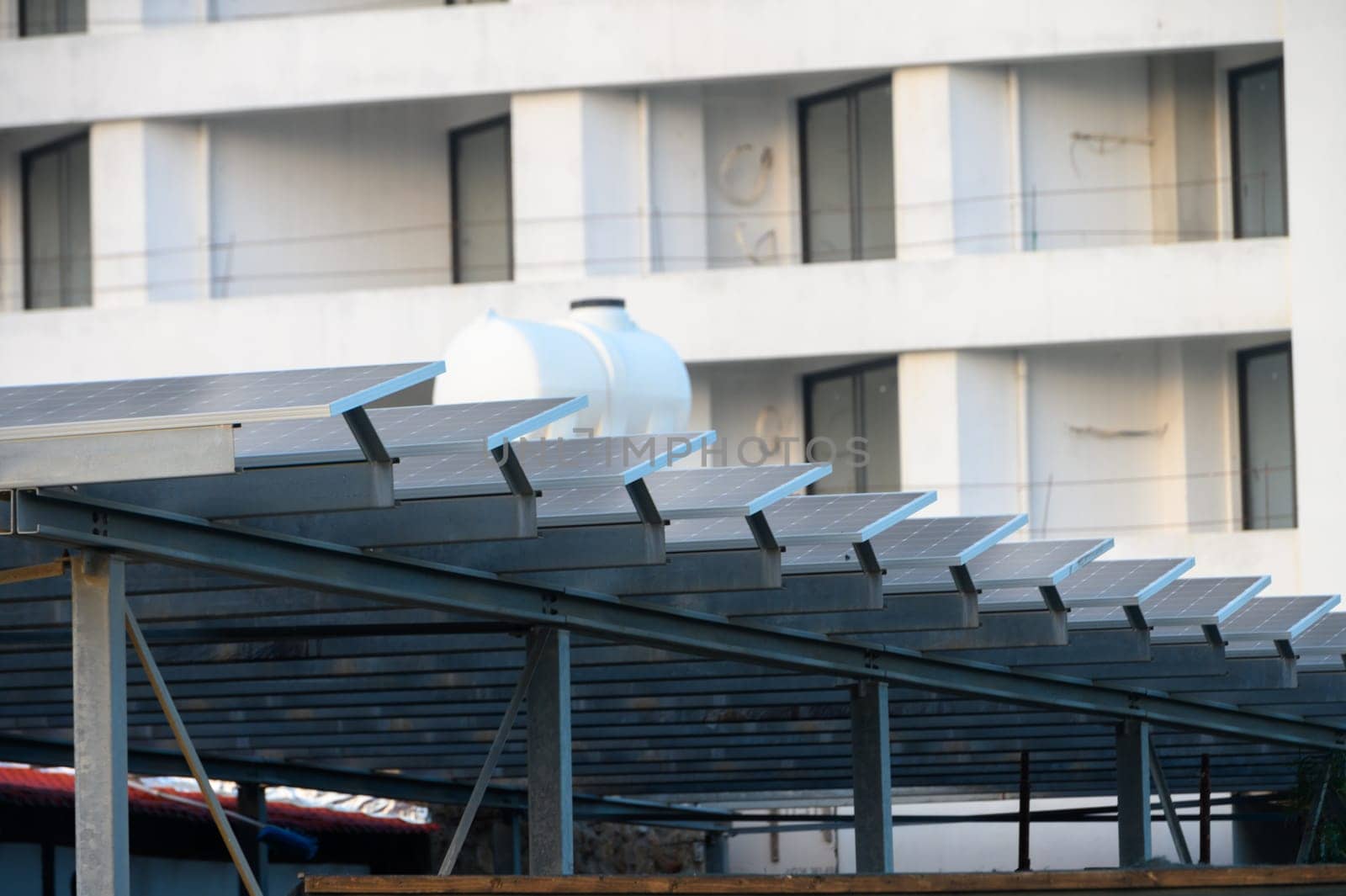 Solar panels line a structure, harnessing energy under bright conditions amid contemporary buildings nearby.