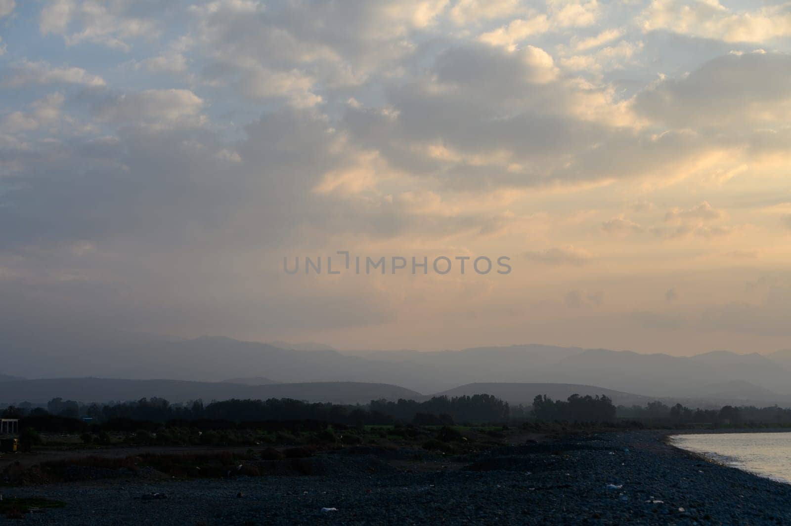 Gentle waves lap at the quiet shore as the sky transforms with pastel hues during a calm evening dusk.