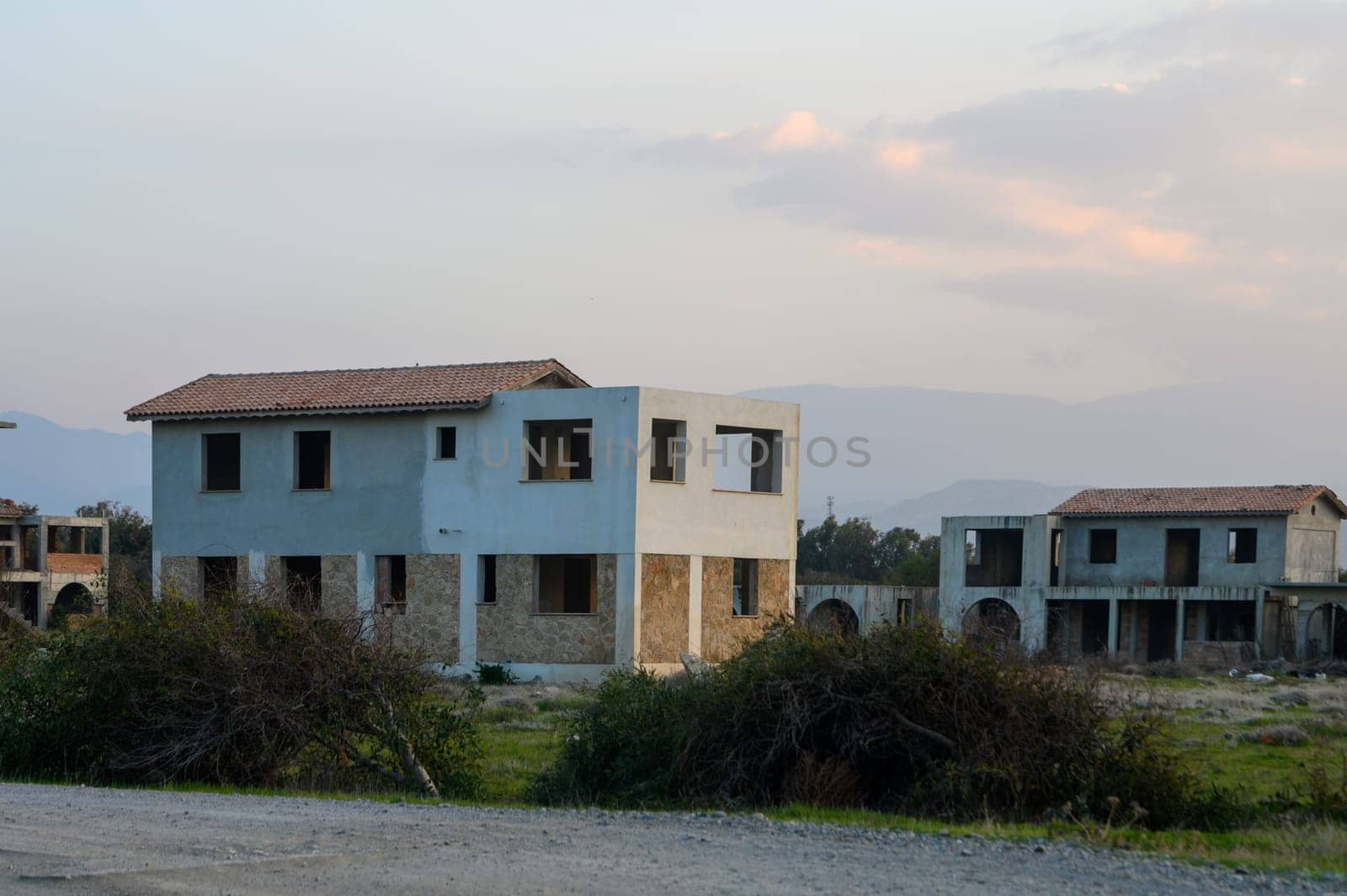 Abandoned structures emerge among overgrown weeds, bathed in the warm glow of twilight, evoking a sense of nostalgia.