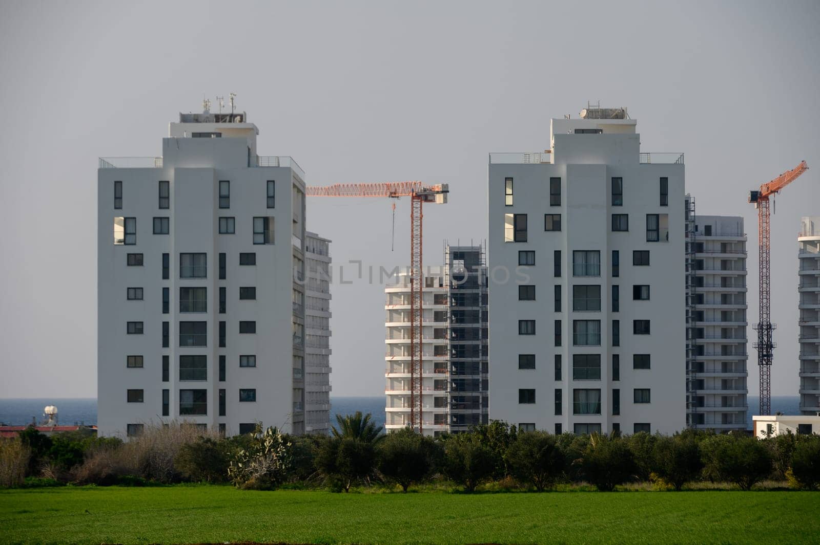 Twin towers rise above lush greenery, showcasing contemporary architecture while construction work continues nearby.