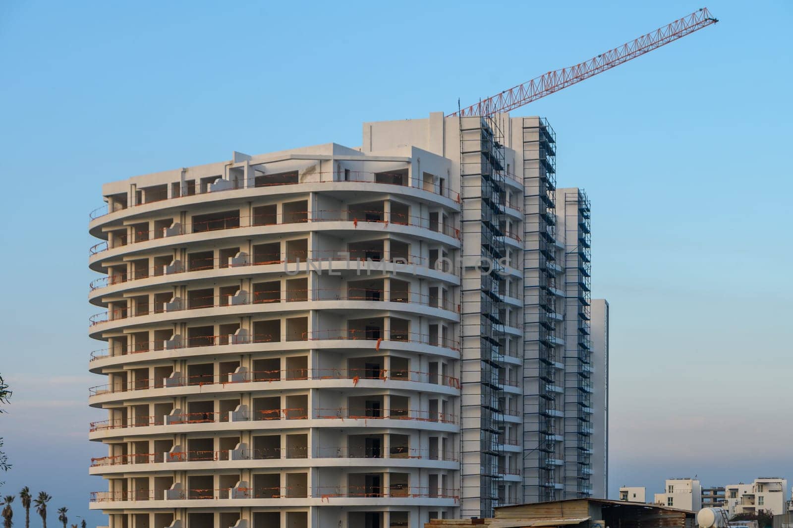 A modern building under construction stands tall, showcasing its circular design and vibrant environment at dusk.