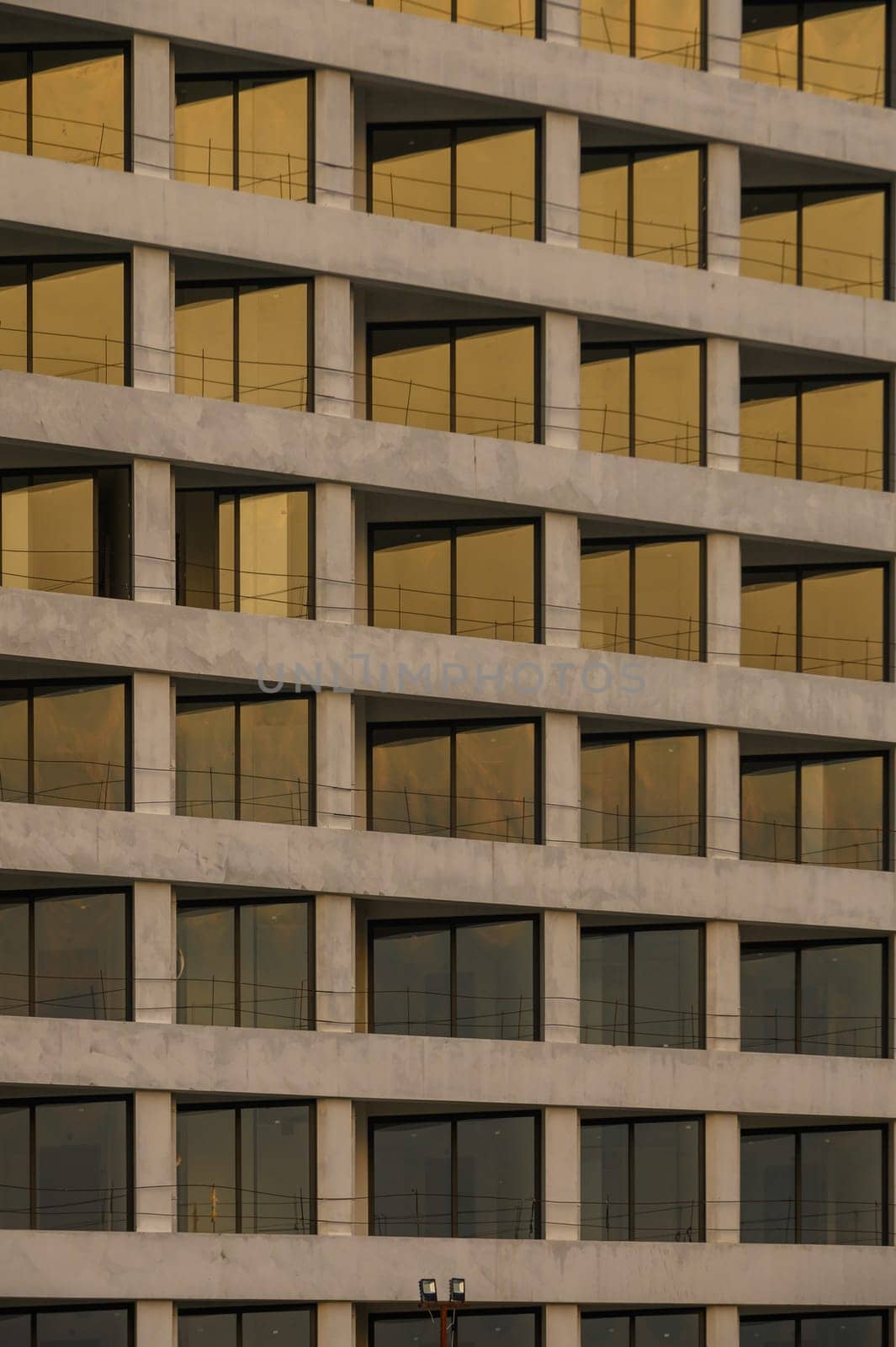 Golden hues reflect off large windows of a contemporary structure during twilight, showcasing modern design elements.