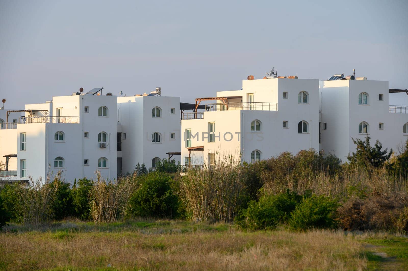 White architectural structures contrast beautifully with lush greenery under the warm glow of the setting sun.