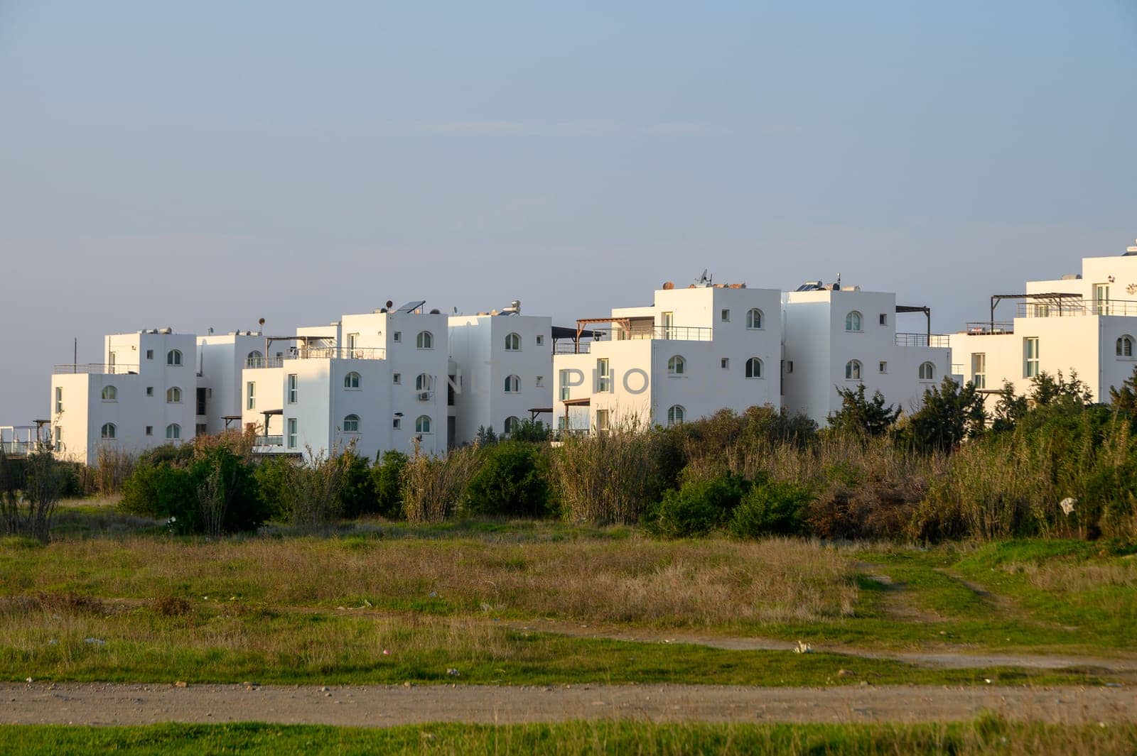 Bright white structures rise amidst lush greenery, capturing the warmth of a sunset in a peaceful setting.