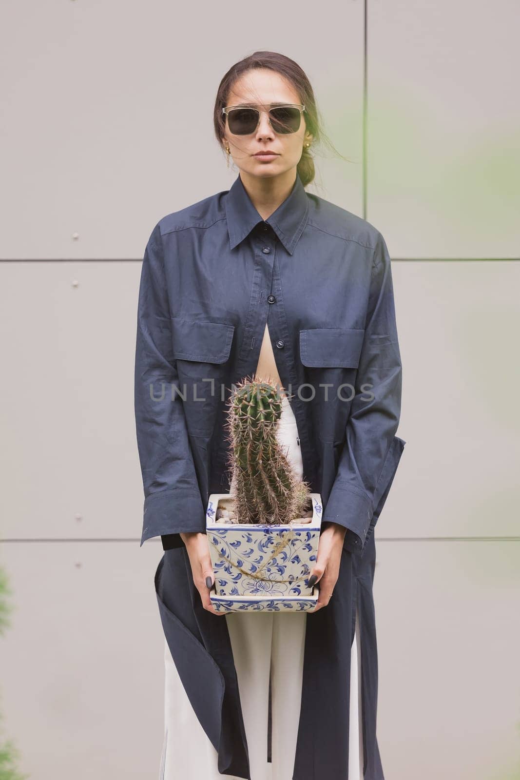 Woman tenderly standing in kimono with cactus in her hands on gray background. by sarymsakov