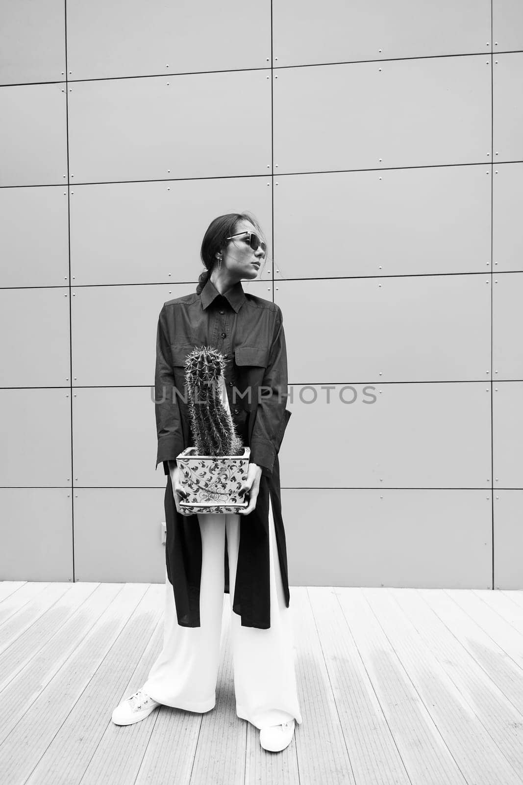 Woman tenderly standing in kimono with cactus in her hands on gray background. by sarymsakov