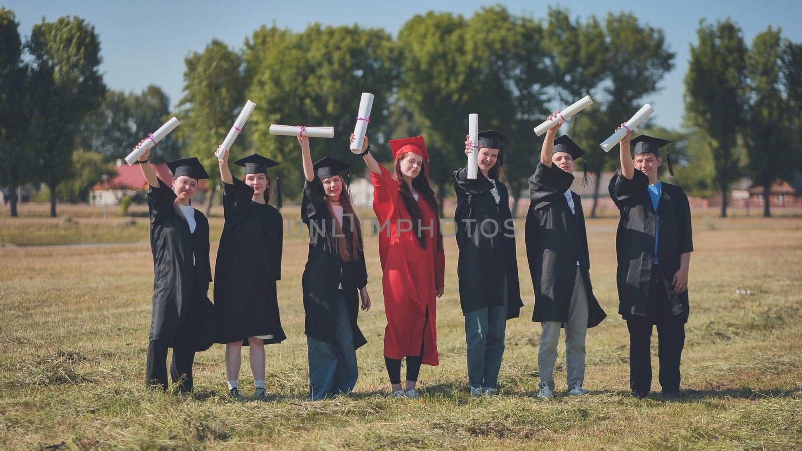 Young graduates pose and wave diplomas in their hands in the street