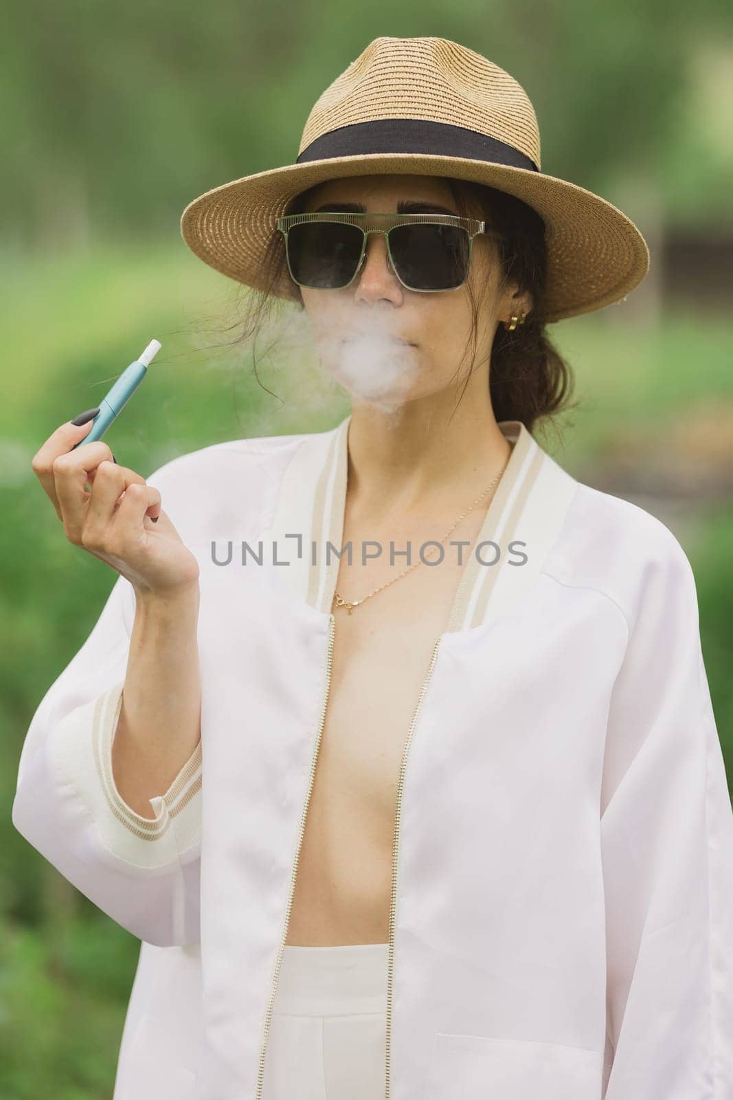 beautiful woman smoking electronic cigarette in street. by sarymsakov