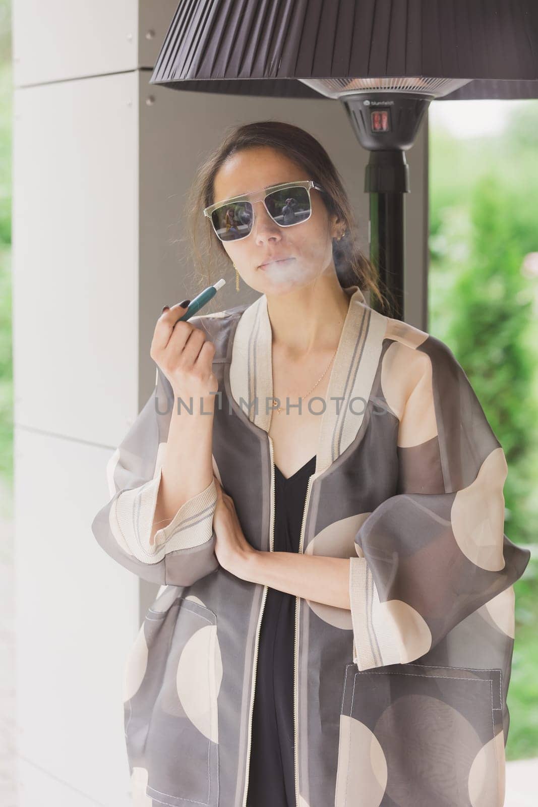 beautiful woman smoking electronic cigarette in street by sarymsakov