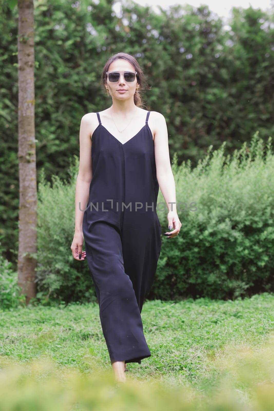 Beautiful young brunette woman, wearing black jumpsuit posing outdoors. Street fashion. Stylish outfit