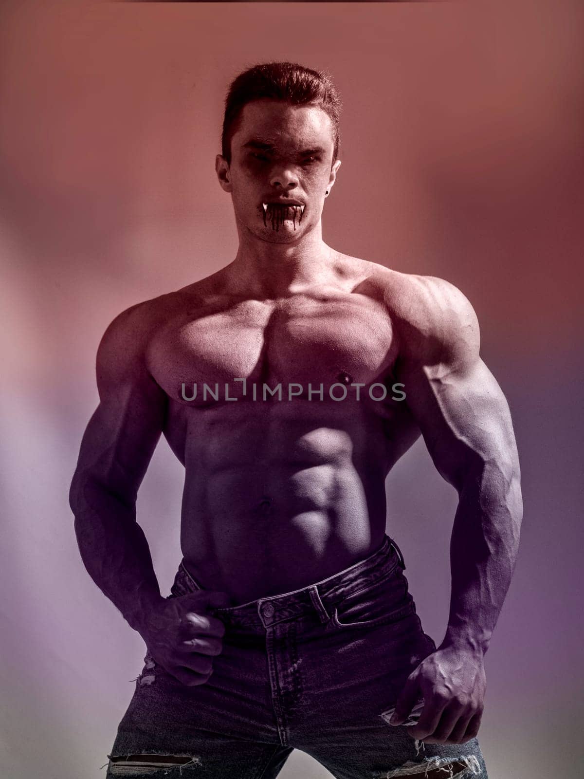 Portrait of a Young Muscular Vampire Man Shirtless, Showing his Torso, Chest and Abs, Looking at the Camera, on Dark Background for Halloween