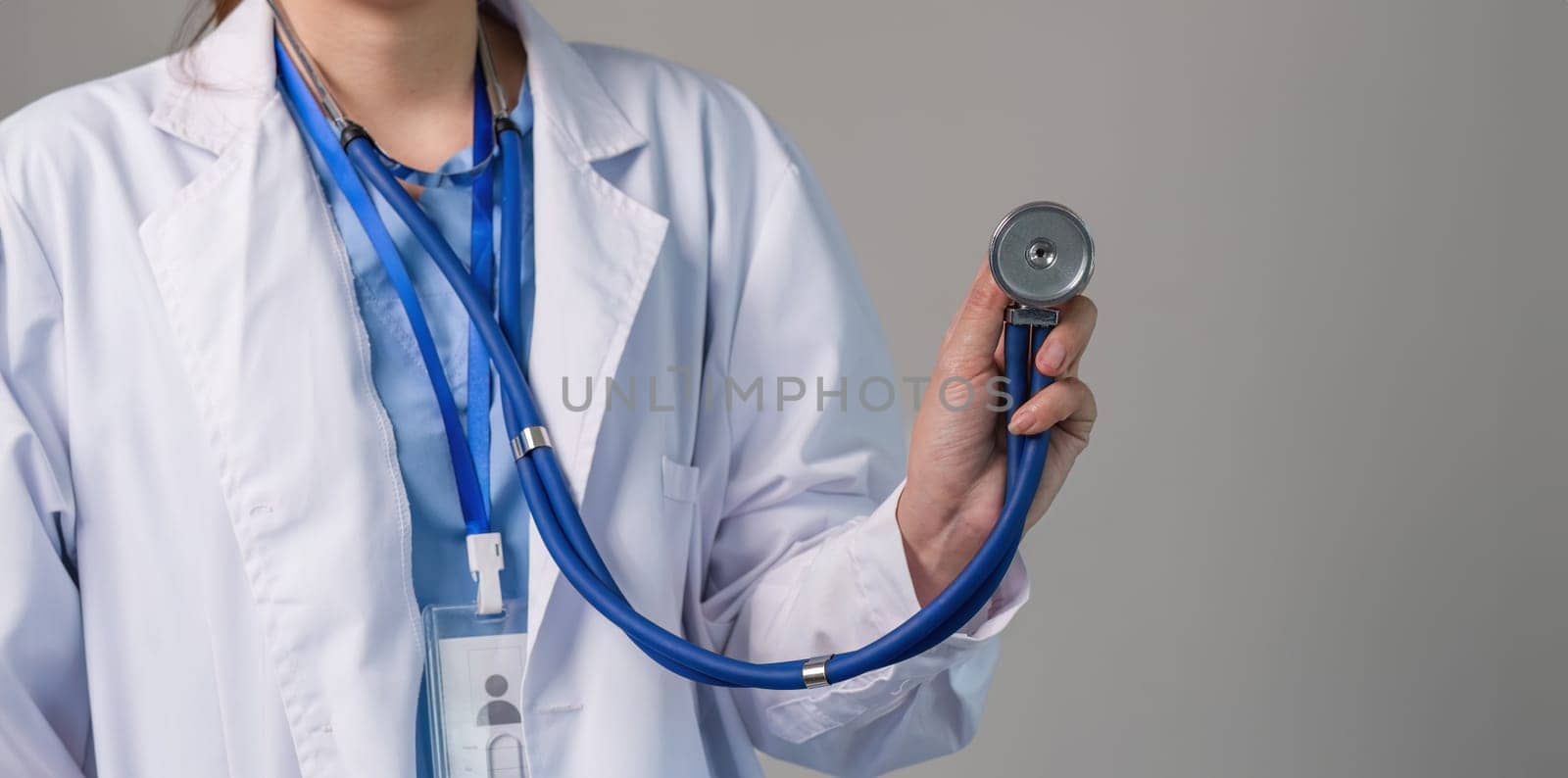 Close up female doctor using stethoscope on flat background. health care concept Female doctor using equipment to check patient's health by wichayada