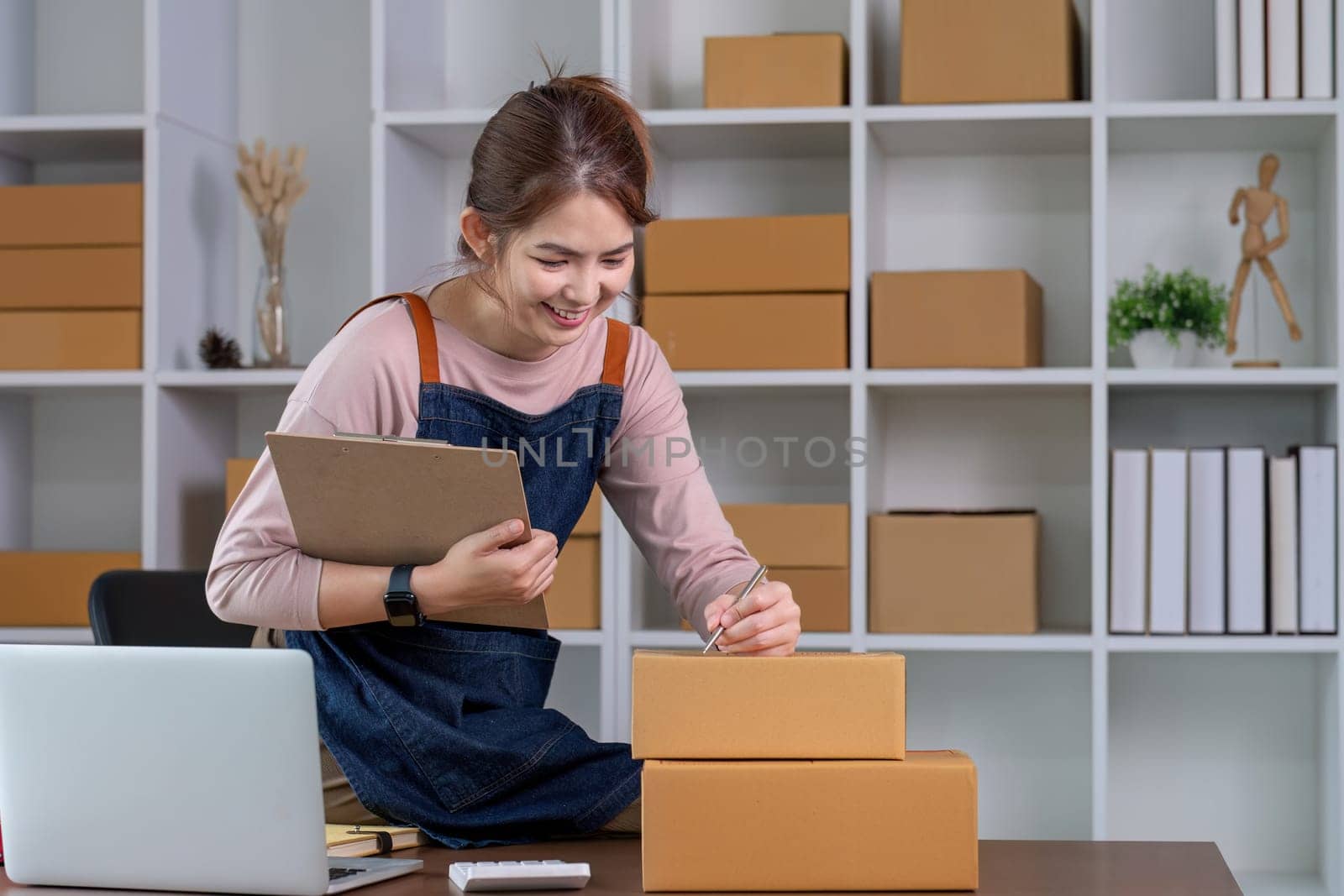 Startup small business entrepreneur SME, asian woman packing cloth in box. Portrait young Asian small business owner home office, online sell marketing delivery, SME e-commerce telemarketing concept by wichayada