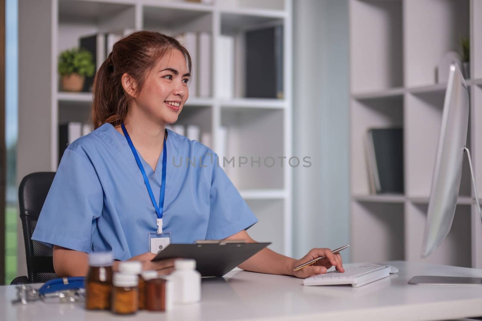 Beautiful Asian doctor smiling using laptop computer explaining detailed medical information online at hospital health medical concept..