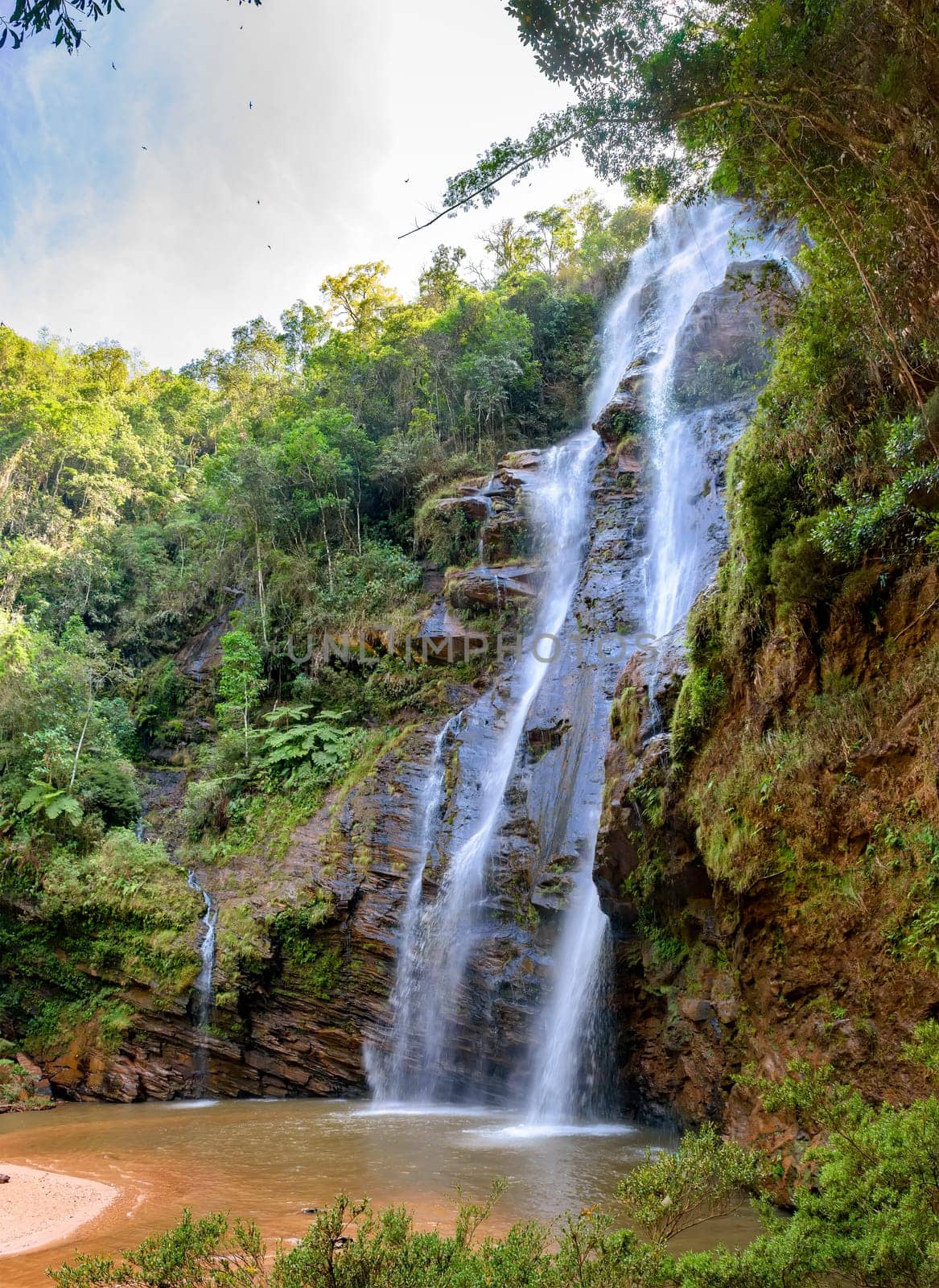 Stunning waterfall among the dense vegetation and rocks of the rainforest in the state of Minas Gerais, Brazil
