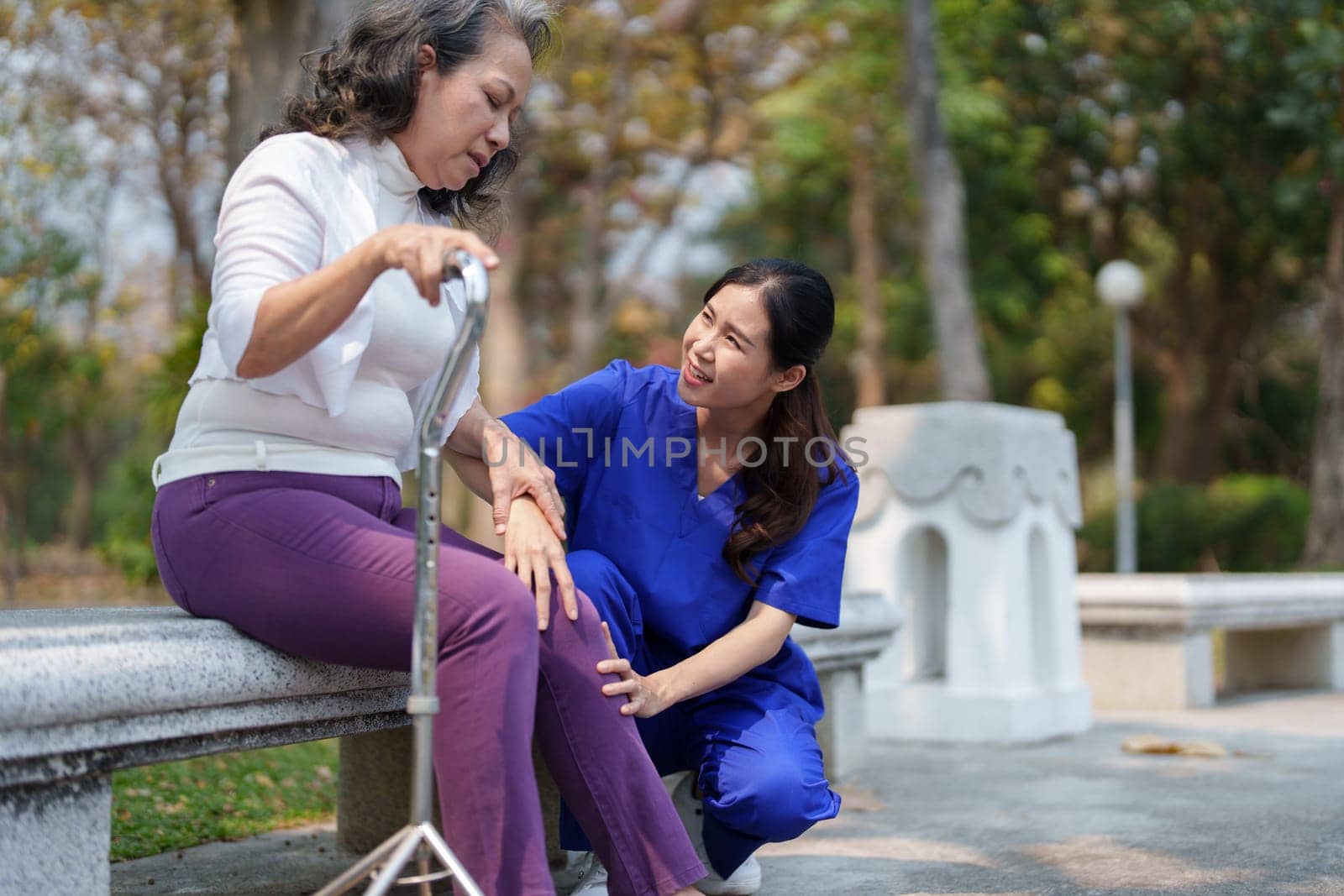 Patient care, female care, young Asian women are taking care of the elderly, providing crutches and walking for patients, and exercising their legs and knees in the park parks