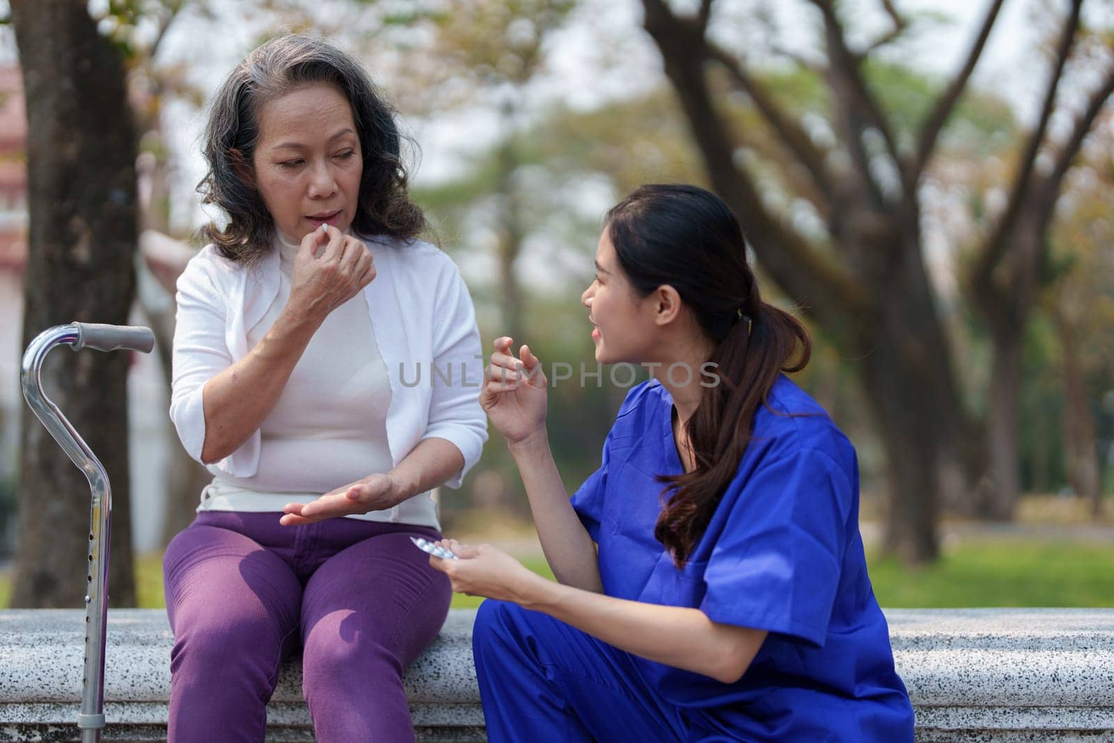 Patient care, female care, young Asian women are taking care of the elderly, providing crutches and walking for patients, and exercising their legs and knees in the park parks