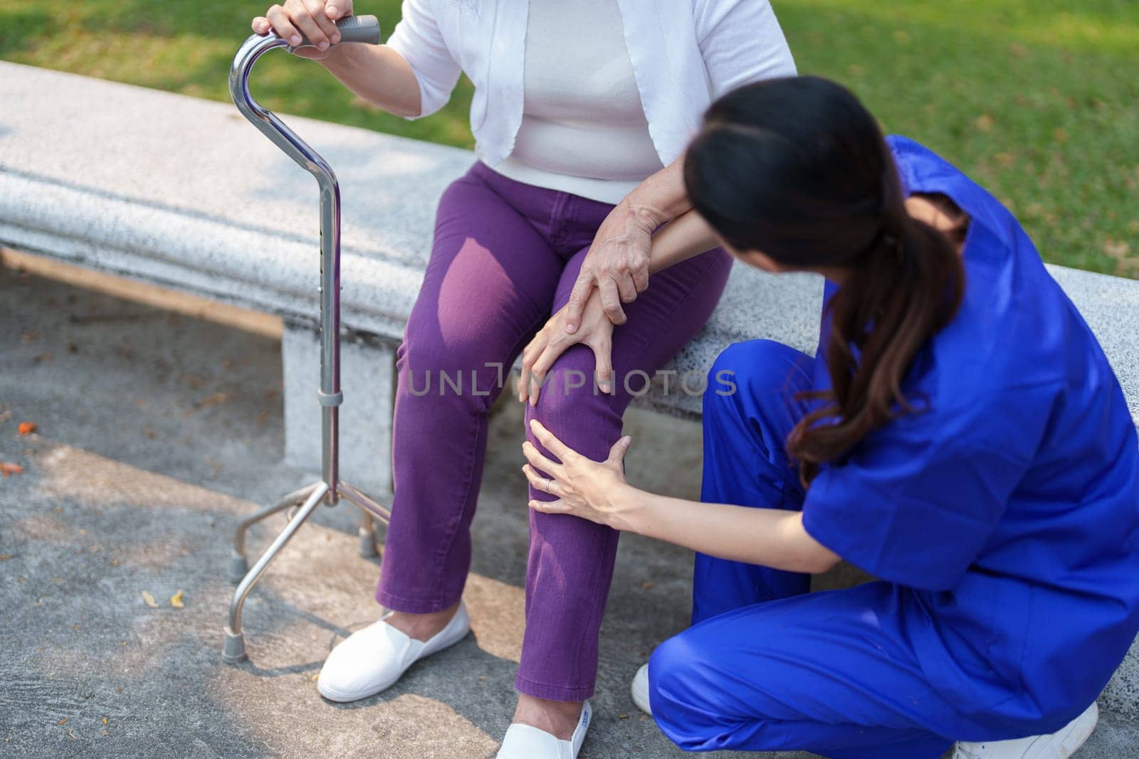 Patient care, female care, young Asian women are taking care of the elderly, providing crutches and walking for patients, and exercising their legs and knees in the park parks. by Manastrong