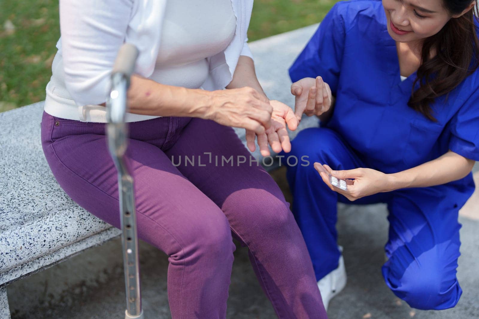 Patient care, female care, young Asian women are taking care of the elderly, providing crutches and walking for patients, and exercising their legs and knees in the park parks. by Manastrong