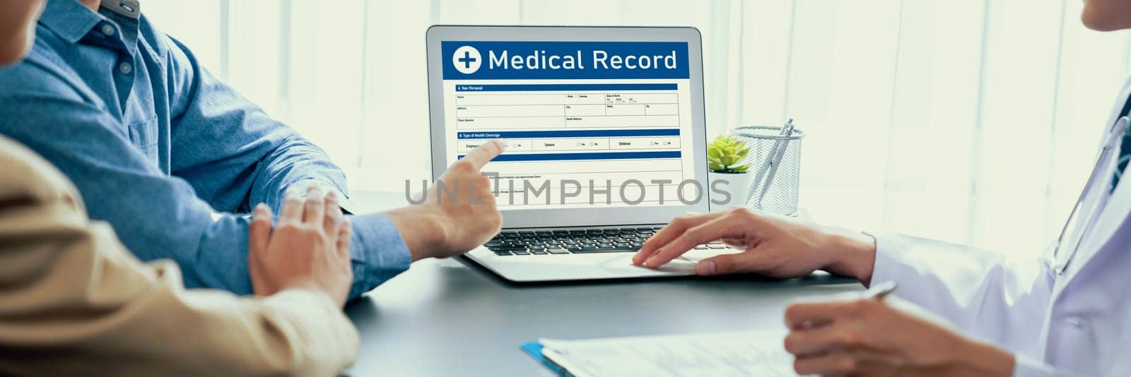 Doctor show medical diagnosis report on laptop and providing compassionate healthcare consultation while young couple patient holding hand and support each other in doctor clinic office. Neoteric