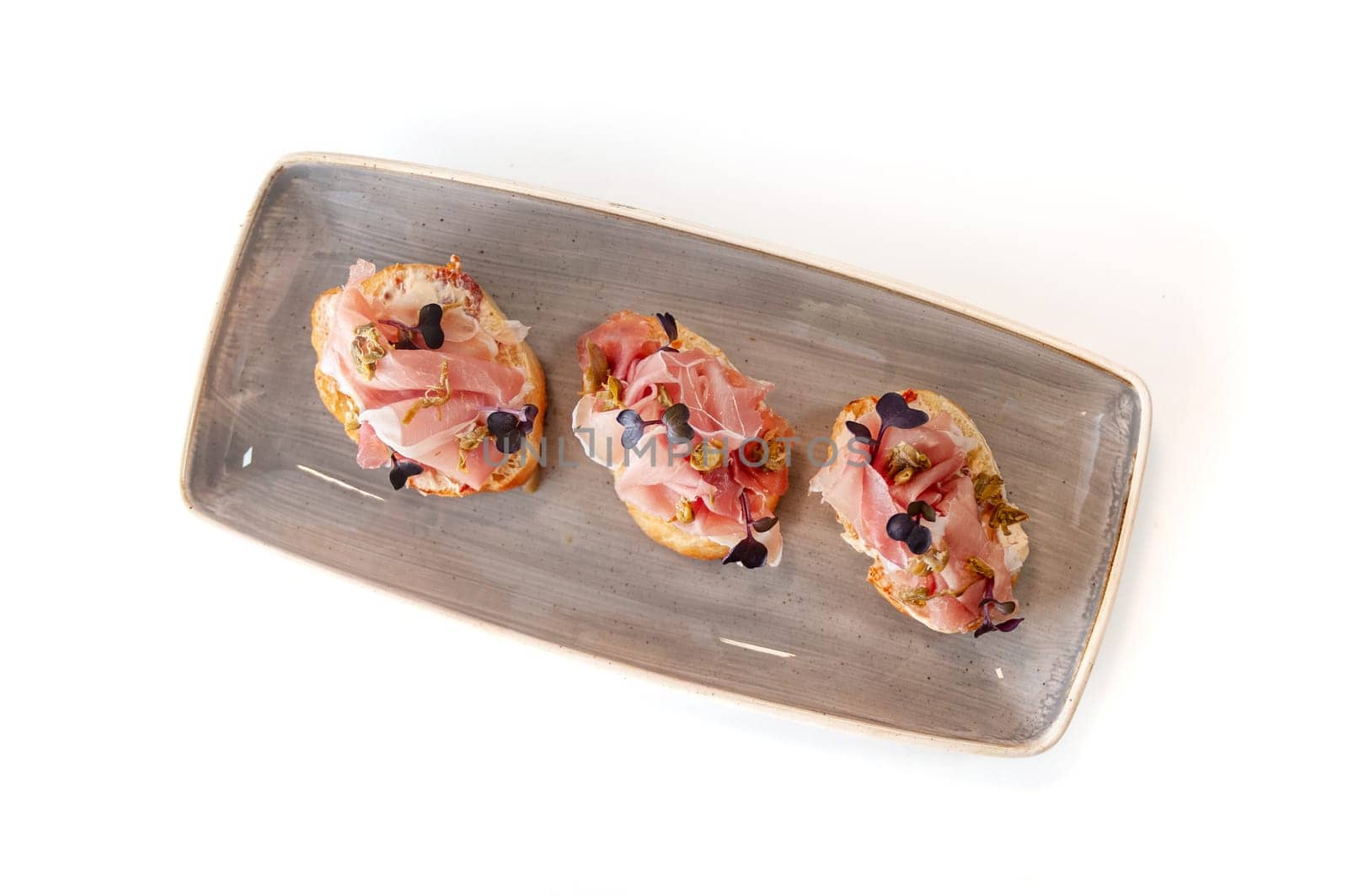 Bruschetta with prosciutto, capers and sun-dried tomatoes on ciabatta toast isolated. High quality photo