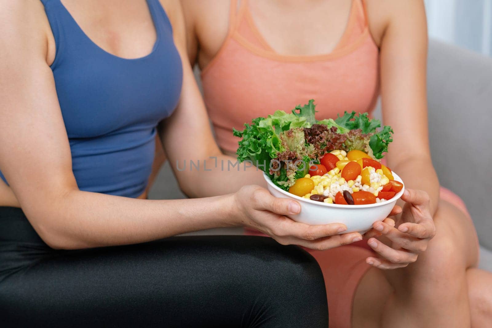 Young sporty Asian women in sportswear holding salad bowl together. Vigorous by biancoblue