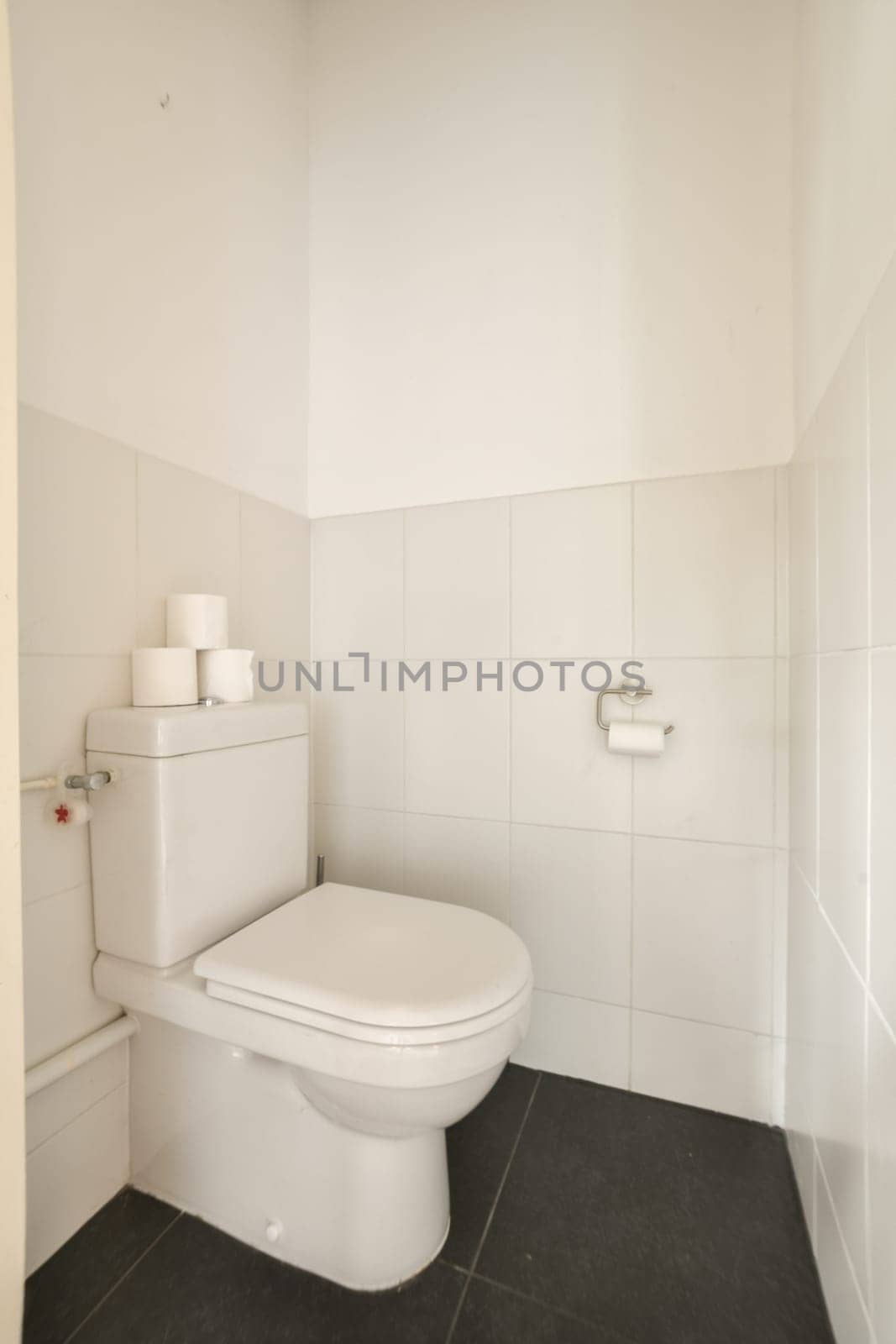 a white bathroom with a toilet and white tiles by casamedia