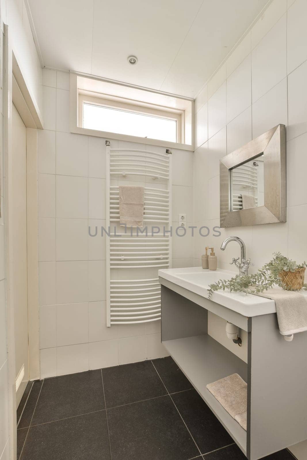 a modern bathroom with black tile flooring and white tiles on the walls, there is a large mirror above the sink