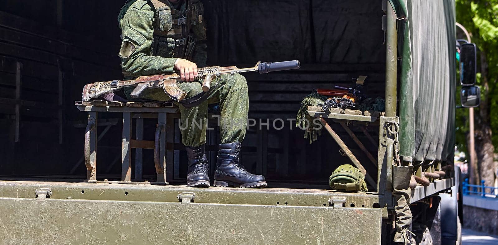 Soldiers unload firearms from a military truck. A soldier in the back of a truck.