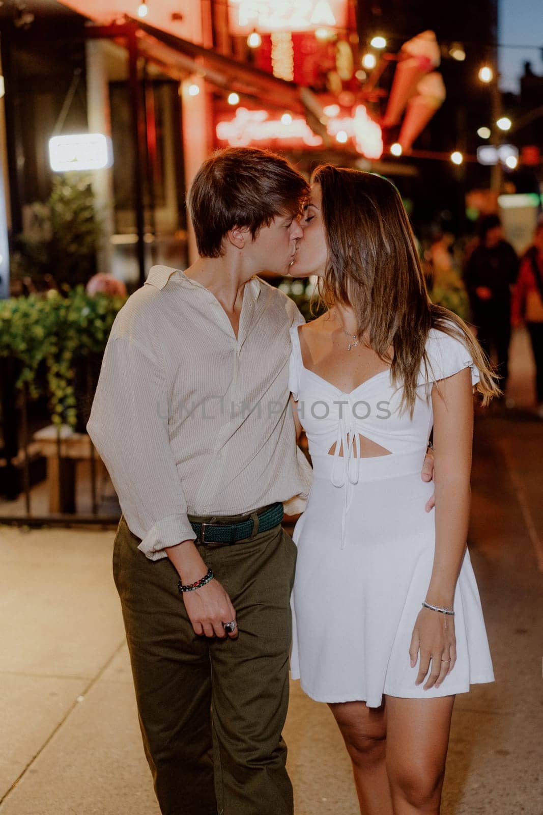 A couple happily enjoying a romantic and intimate walk together at night, dressed in stylish casual clothing