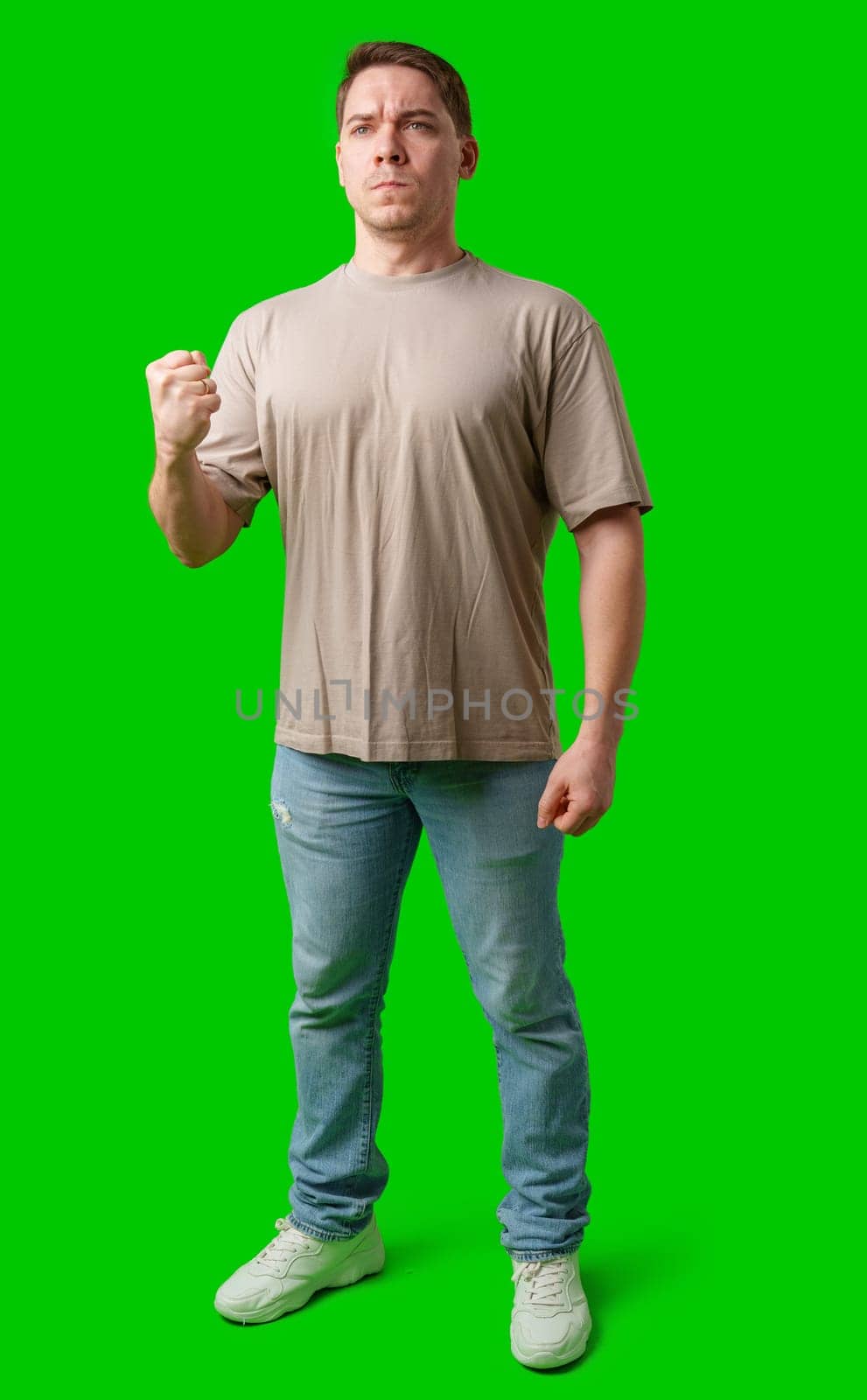 A young man stands confidently in casual attire on a vibrant green background in studio