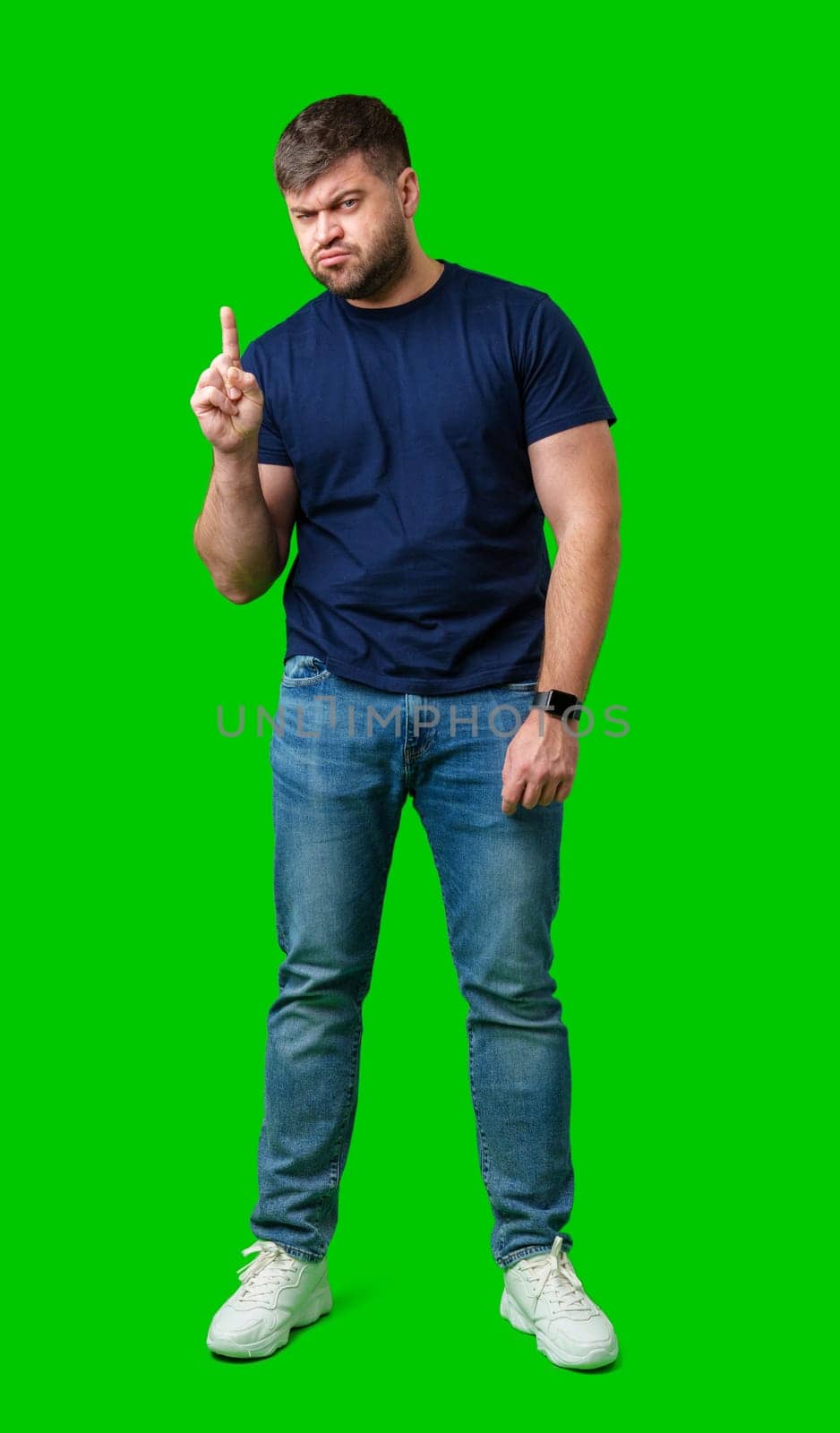 A man thoughtfully ponders on a bright green background in studio