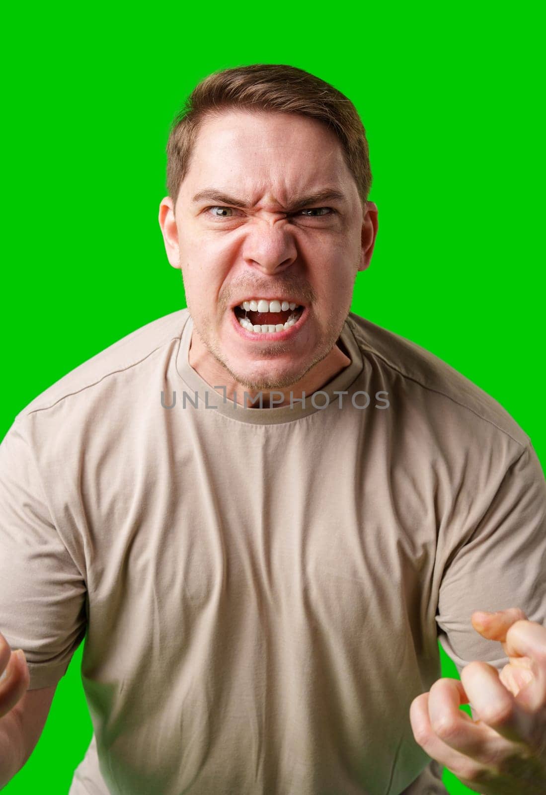 Man expressing intense frustration while standing against a bright green background in studio