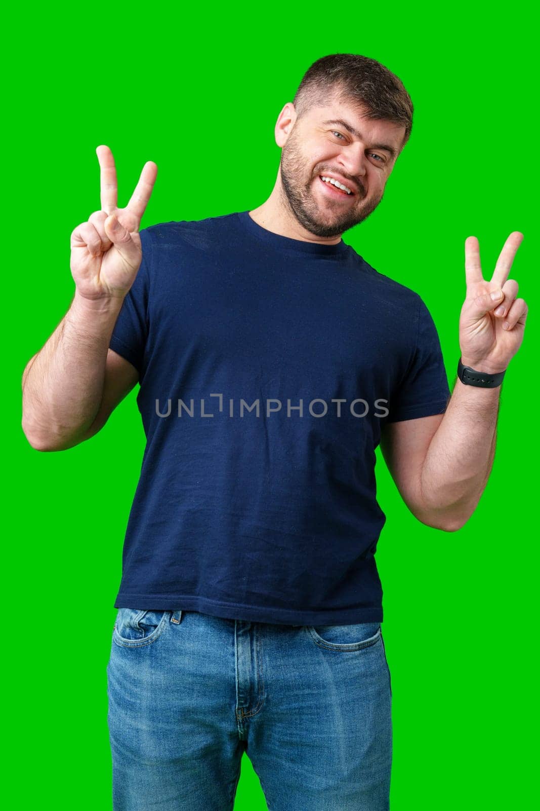 Man smiling and giving peace signs while standing against a bright green backdrop close up