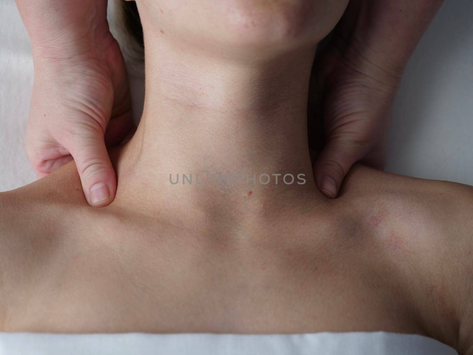 The masseur massages the client in the thoracic area of the collarbone. Close-up, no face