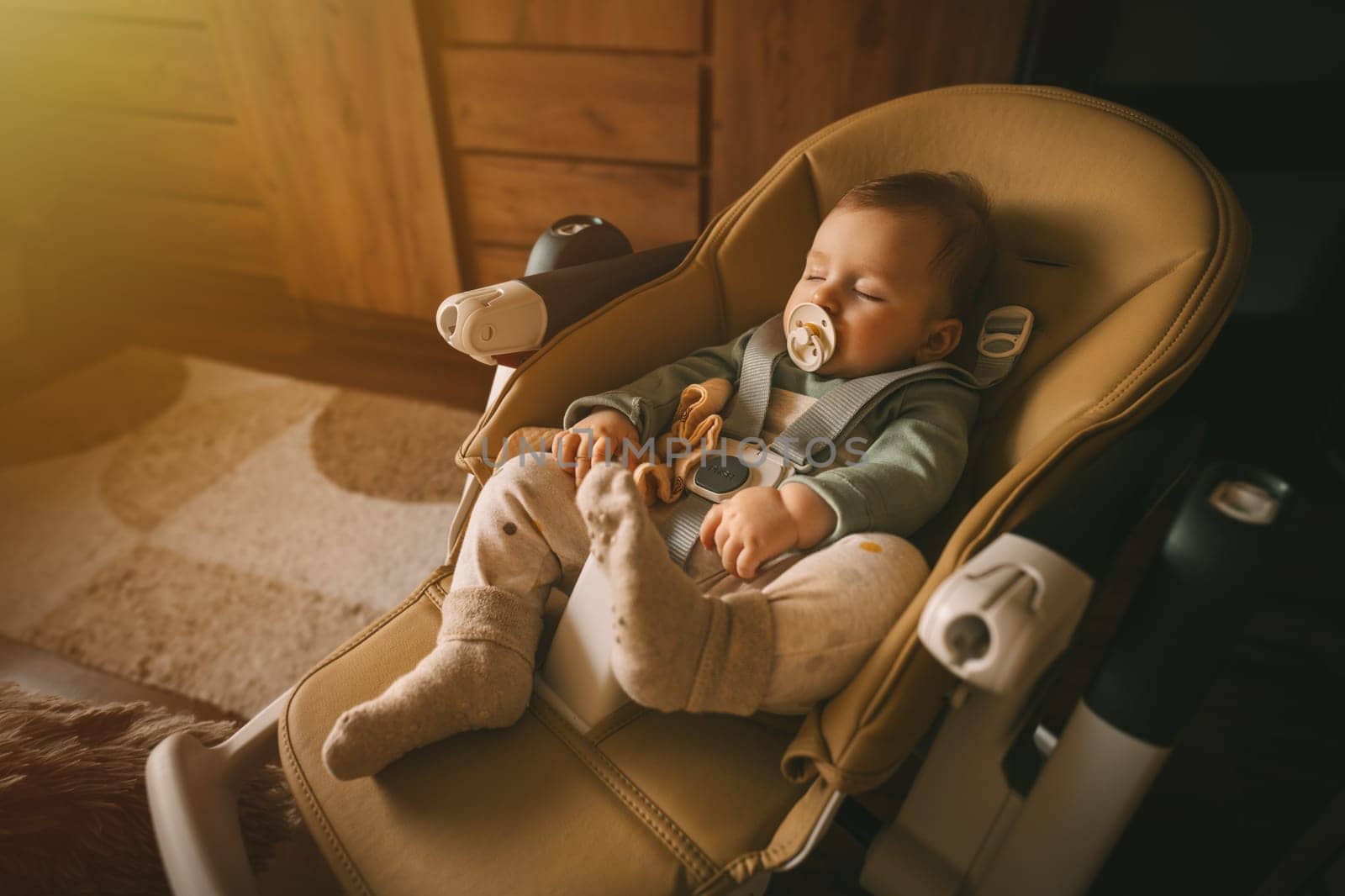 Cute 5-month old baby sleeping in chair with dummy. Adorable kid portrait. Childhood and babyhood concept. High quality photo