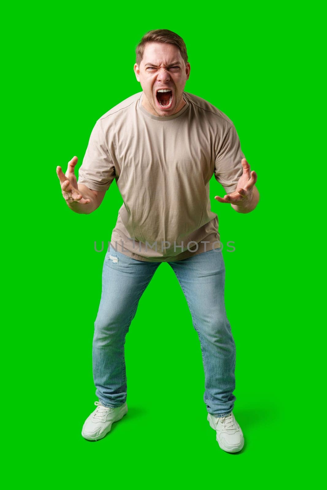 Man expressing intense frustration while standing against a bright green background in studio