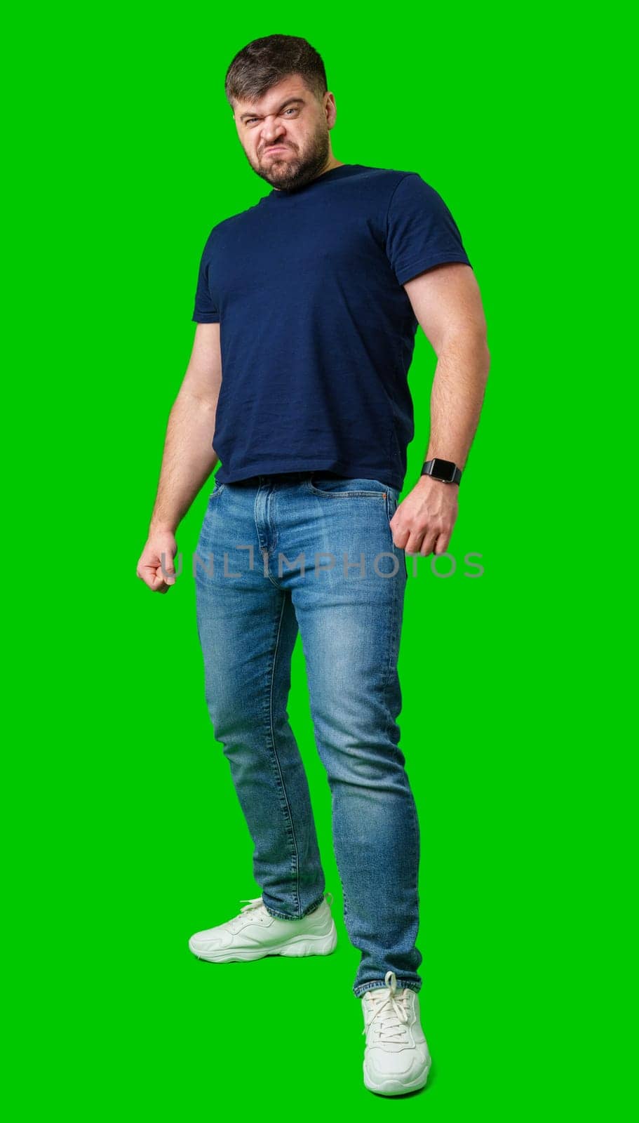 Man expressing confusion with crossed arms in front of a bright green background during a casual moment