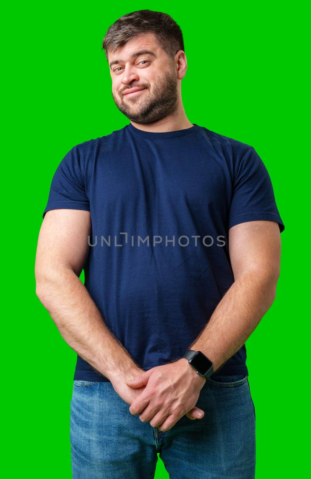 Man standing with a thoughtful expression in a casual outfit against a green background in studio