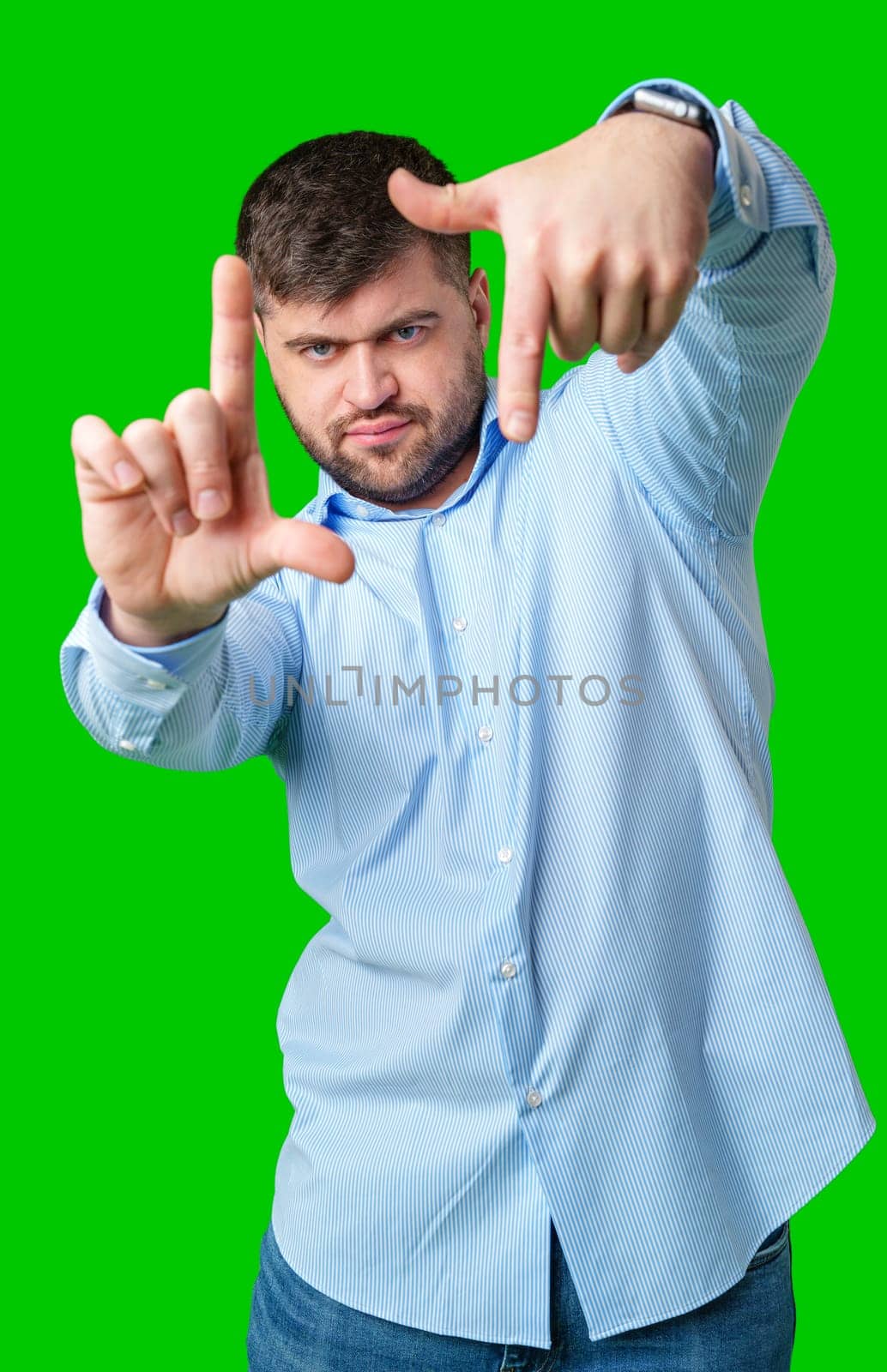 Person gesturing a framing shape with hands in a bright green studio setting close up