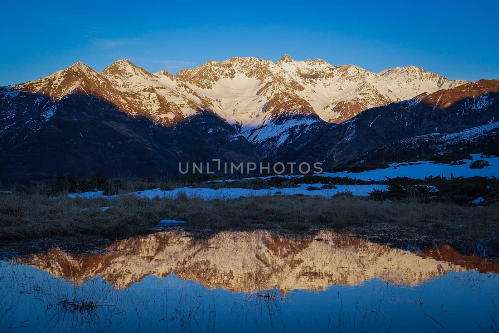 Sunset over the Pyrenees mountains with the reflection of the peaks in the water of the lake High quality 4k footage