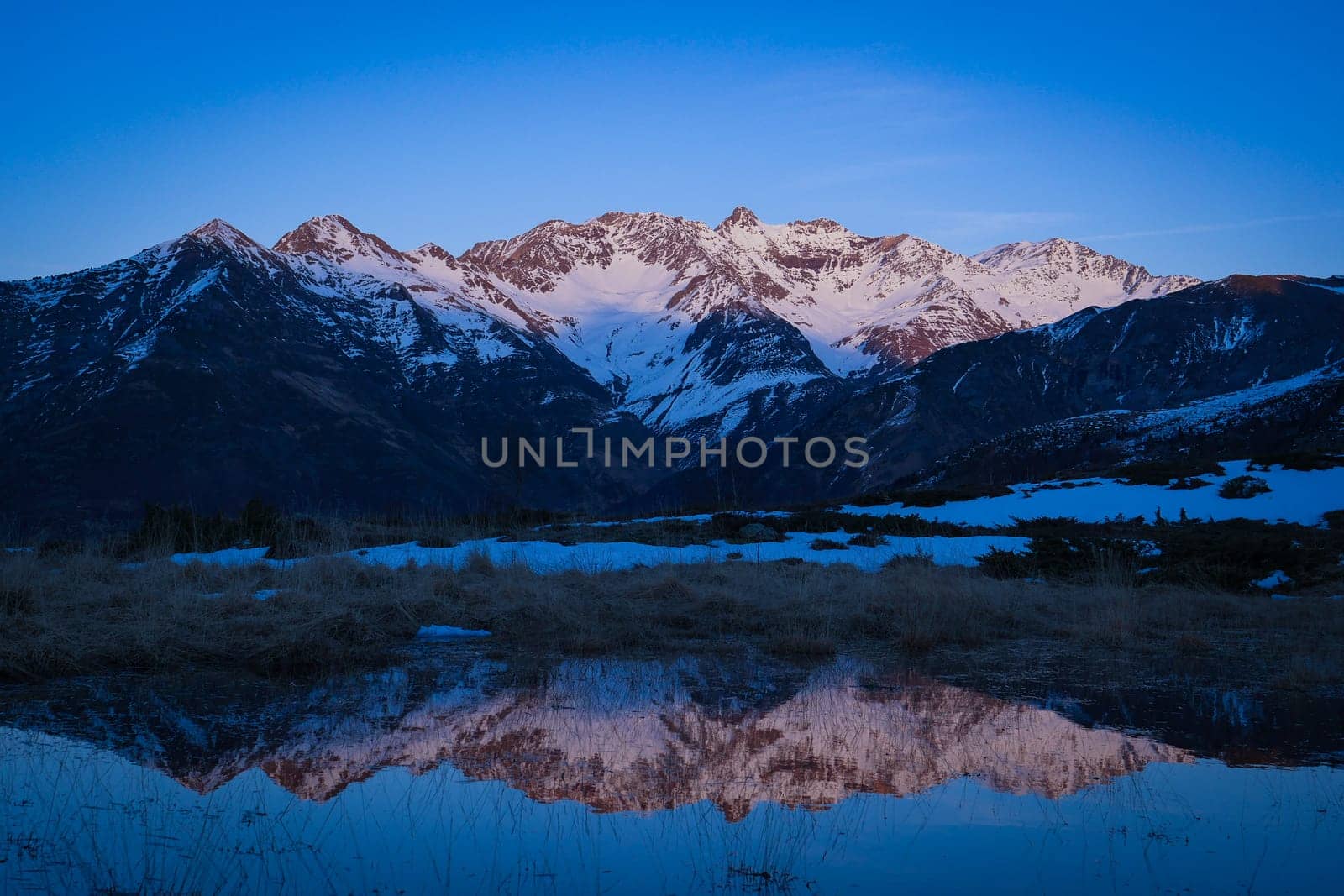Sunset over the Pyrenees mountains with the reflection of the peaks in the water of the lake High quality 4k footage