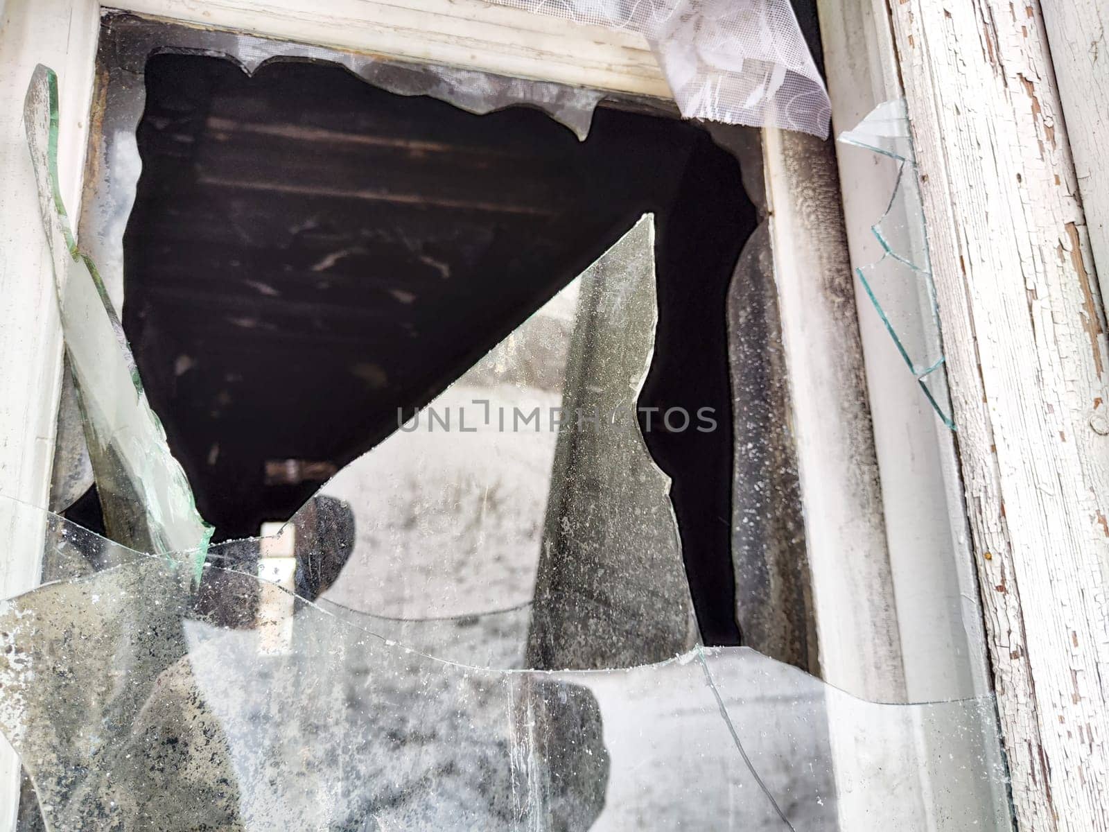 Shattered glass fragments surround an empty space indicating neglect in an abandoned building. Light filters through uneven edges.