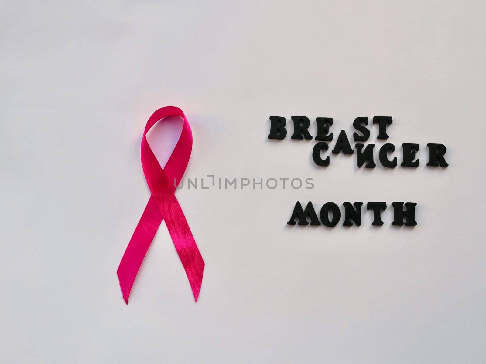 Concept of Breast Cancer Month in Women. Symbol pink ribbon in hands on white background close-up