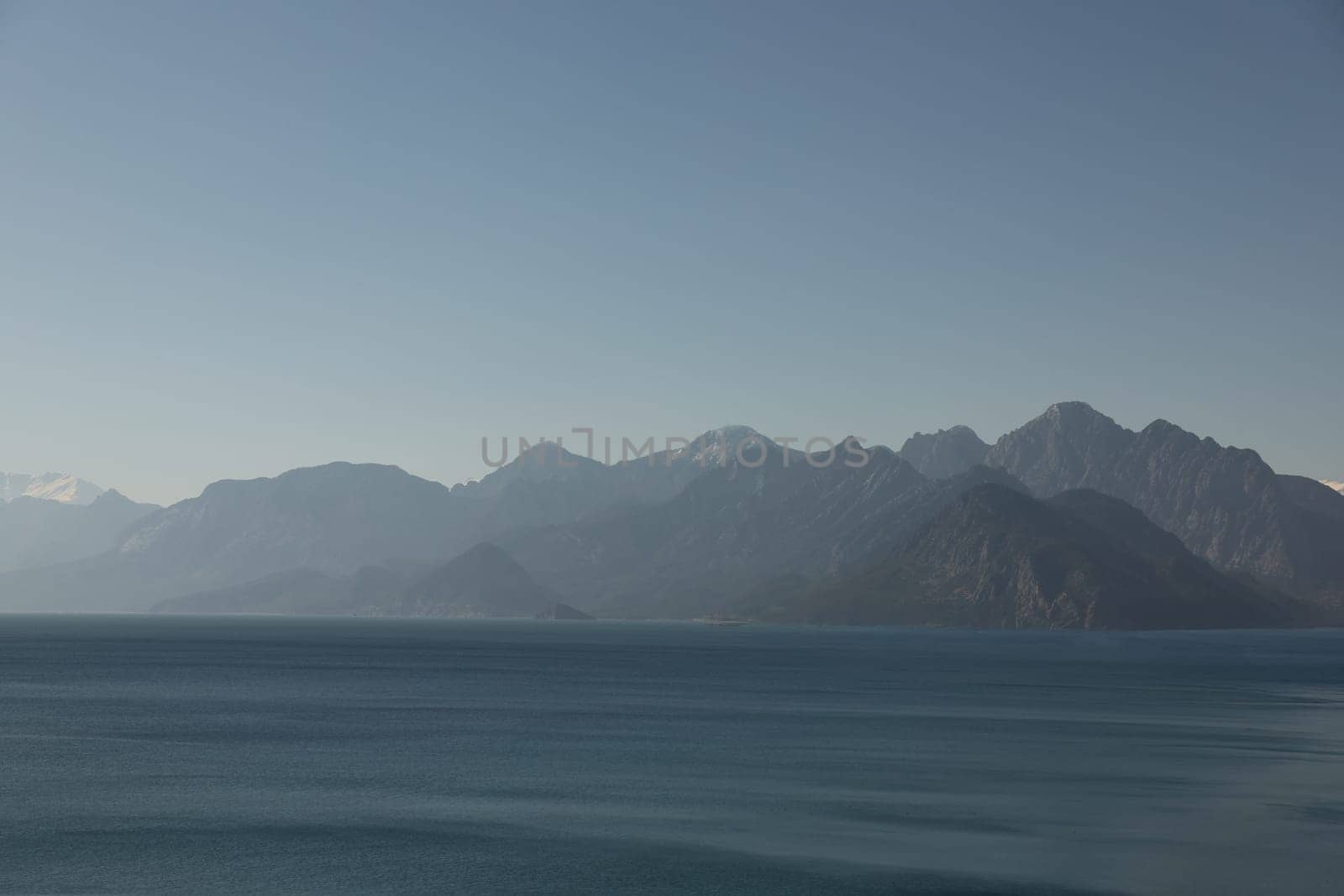 A stunning view of majestic mountains beautifully reflected in calm waters under a clear, bright sky